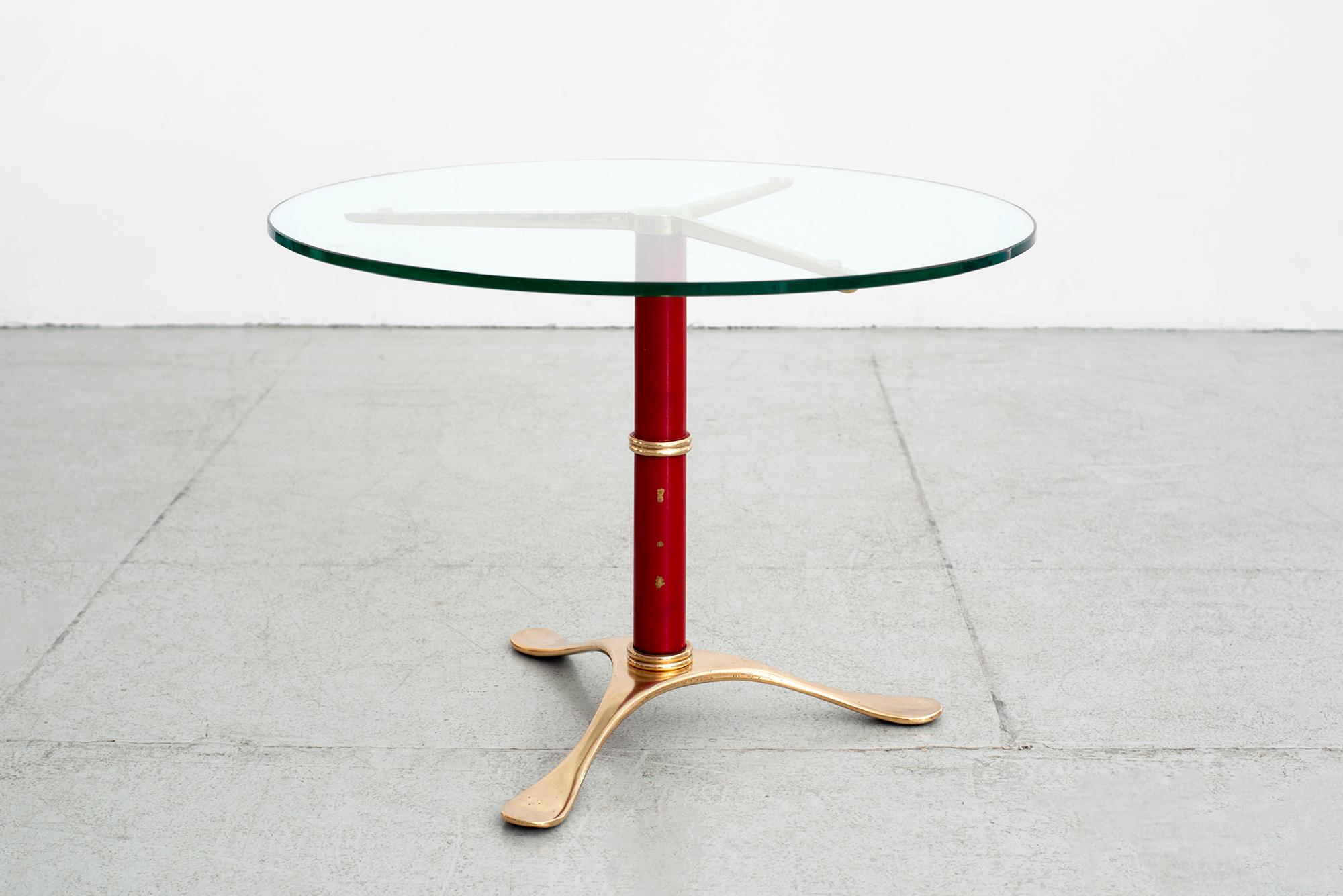 Solid brass tripod table in red enamel, glass top and sculpted brass base.
Beautiful lines and quality.
Slight imperfection to enamel due to age.
  