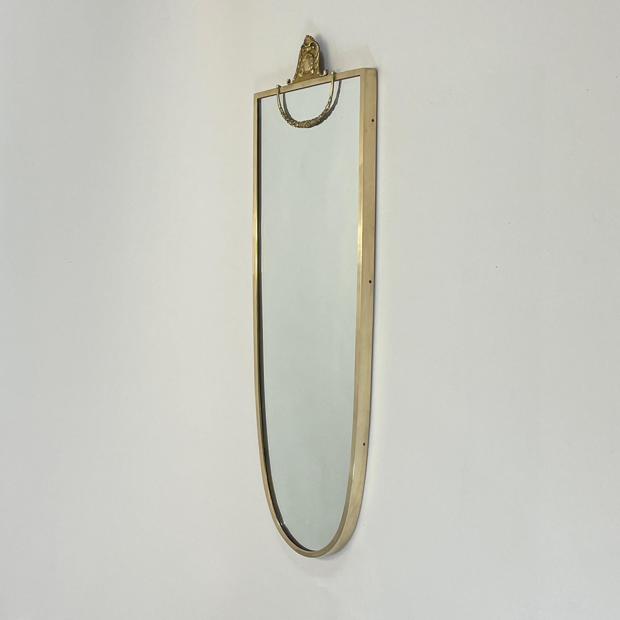 This beautiful Hollywood Regency style wall mirror was designed and manufactured in Italy in the late 1940s to early 1950s. It features a solid brass shield shaped frame and mirror glass.

The overall condition is very good with a nice warm tone to