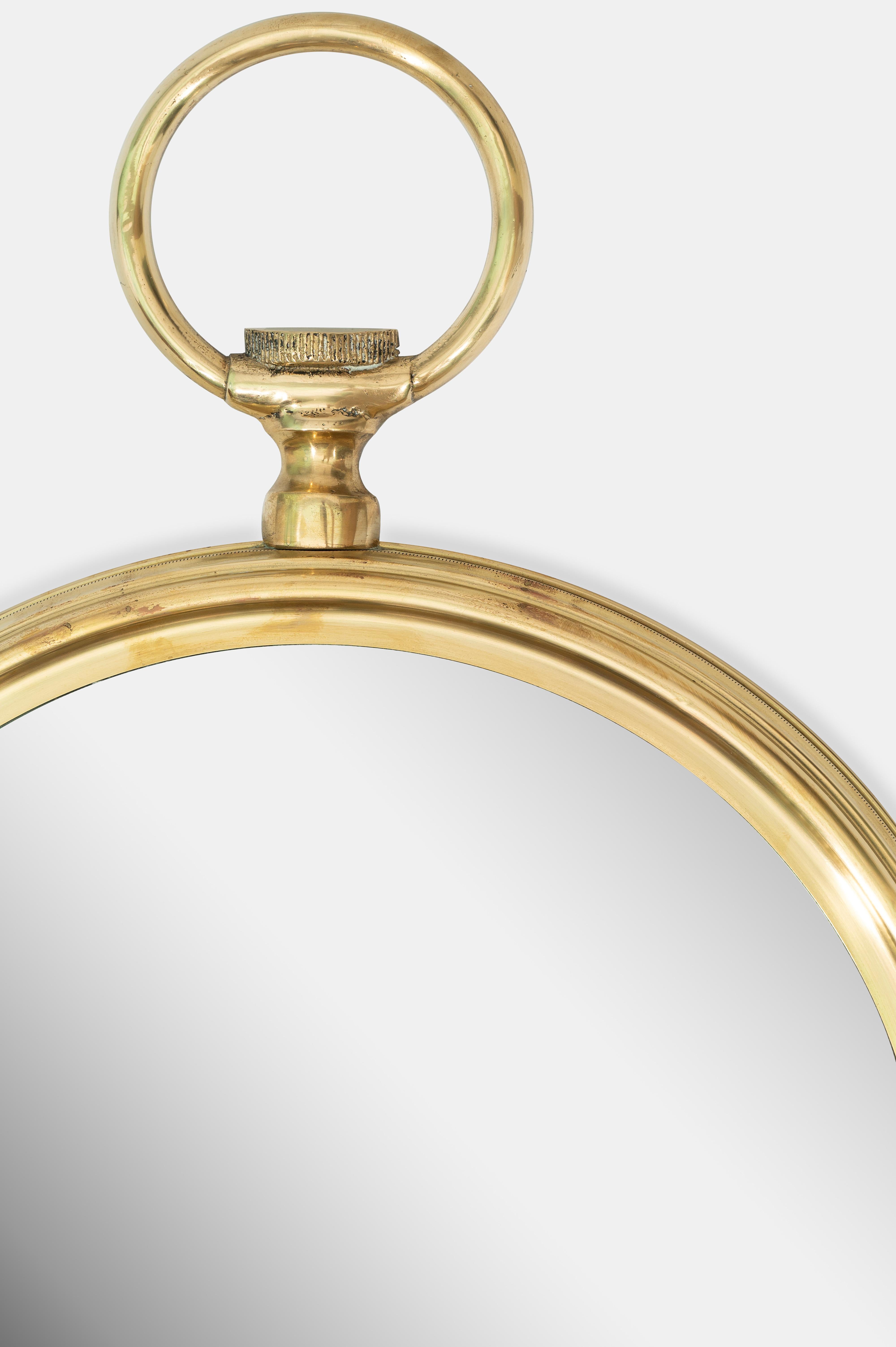 Miroir rond italien, circa 1960, en forme de montre de poche. 
Cadre et crochet de suspension en laiton et verre miroir
Fabriqué en Italie.

Dimensions : 51 D x 70 H cm / 20 D x 27.5 H in
