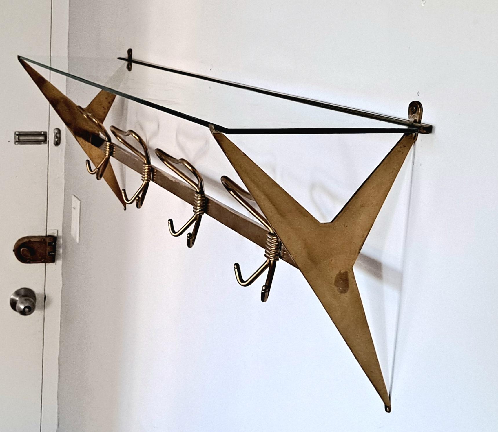 This coat rack made by Fontana Arte in Italy. A beautiful example of elegant design.The coat rack was produced around the 1950s. The frame is made of brass with a glass parcel shelf to store your hats and  caps .