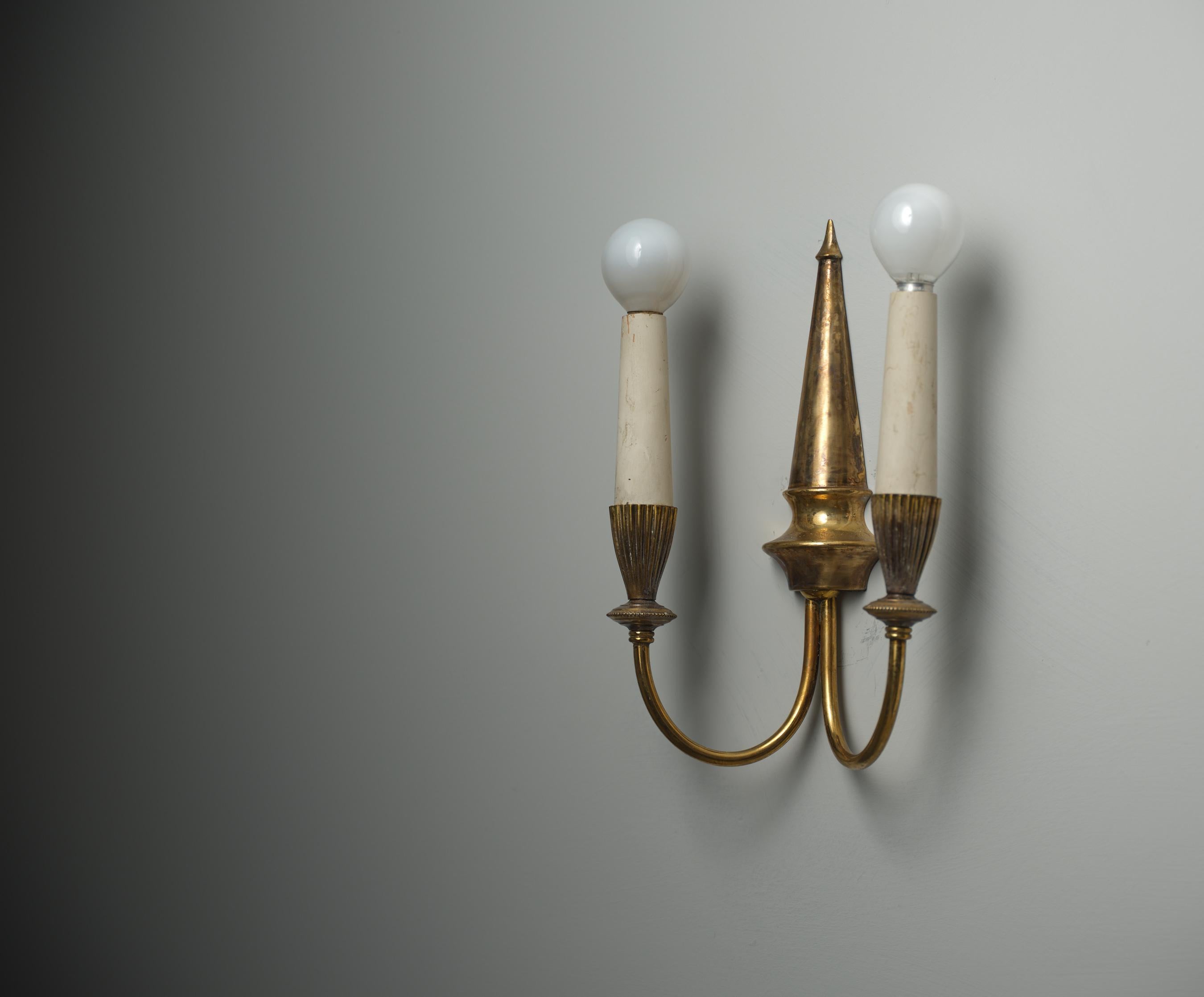 This wall sconce, designed and produced in Italy during the 1950s, features a clean, elegant design crafted entirely in brass. The wall lamps have a distinctive, aged patina and oxidation that adds character and depth to their appearance.
The