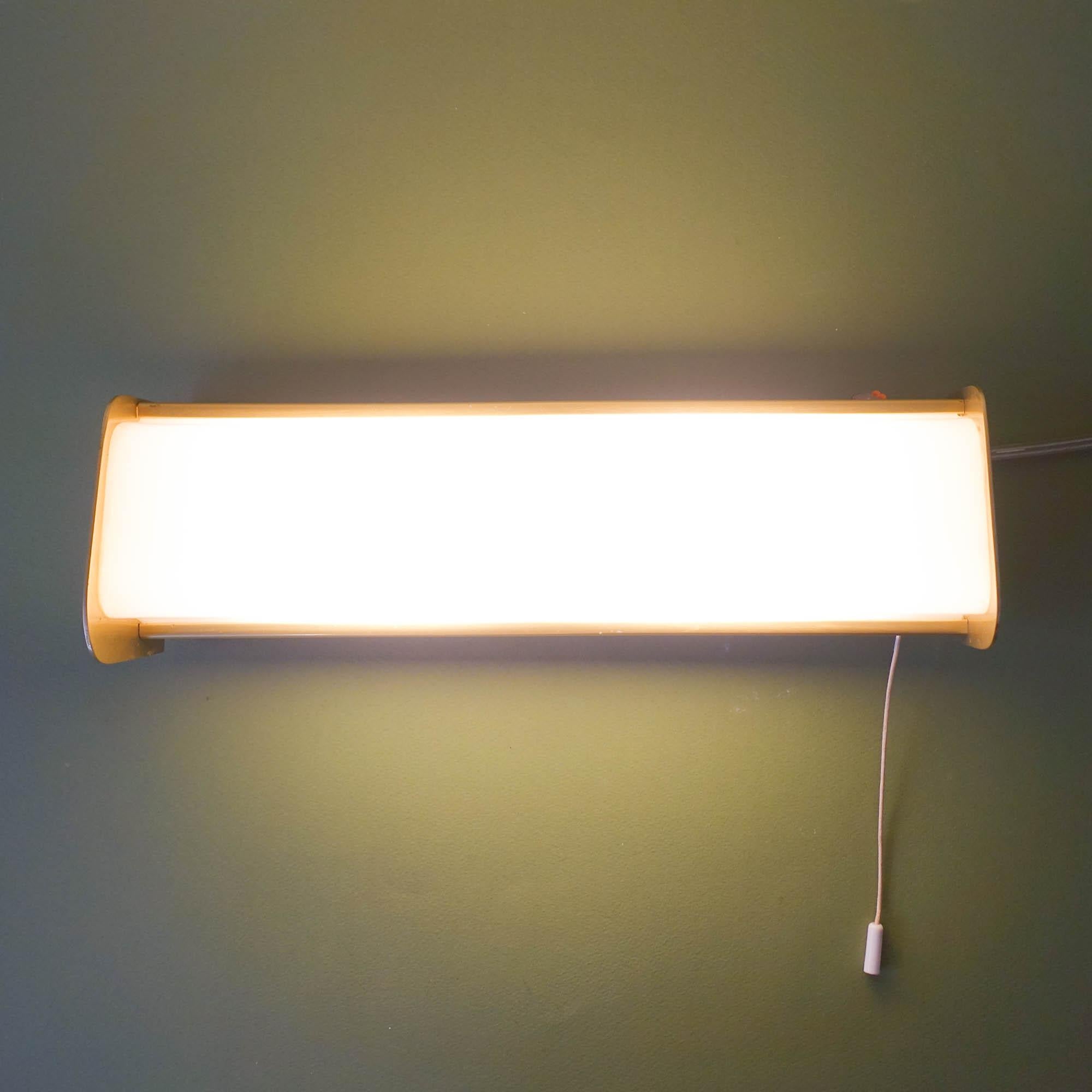 This wall sconce was designed and produced in Italy during the 1950's. The structure is in brass and the shade in white plastic. The laterals have small holes that can spread the light. It fits two E14 bulbs. In original and good vintage condition.