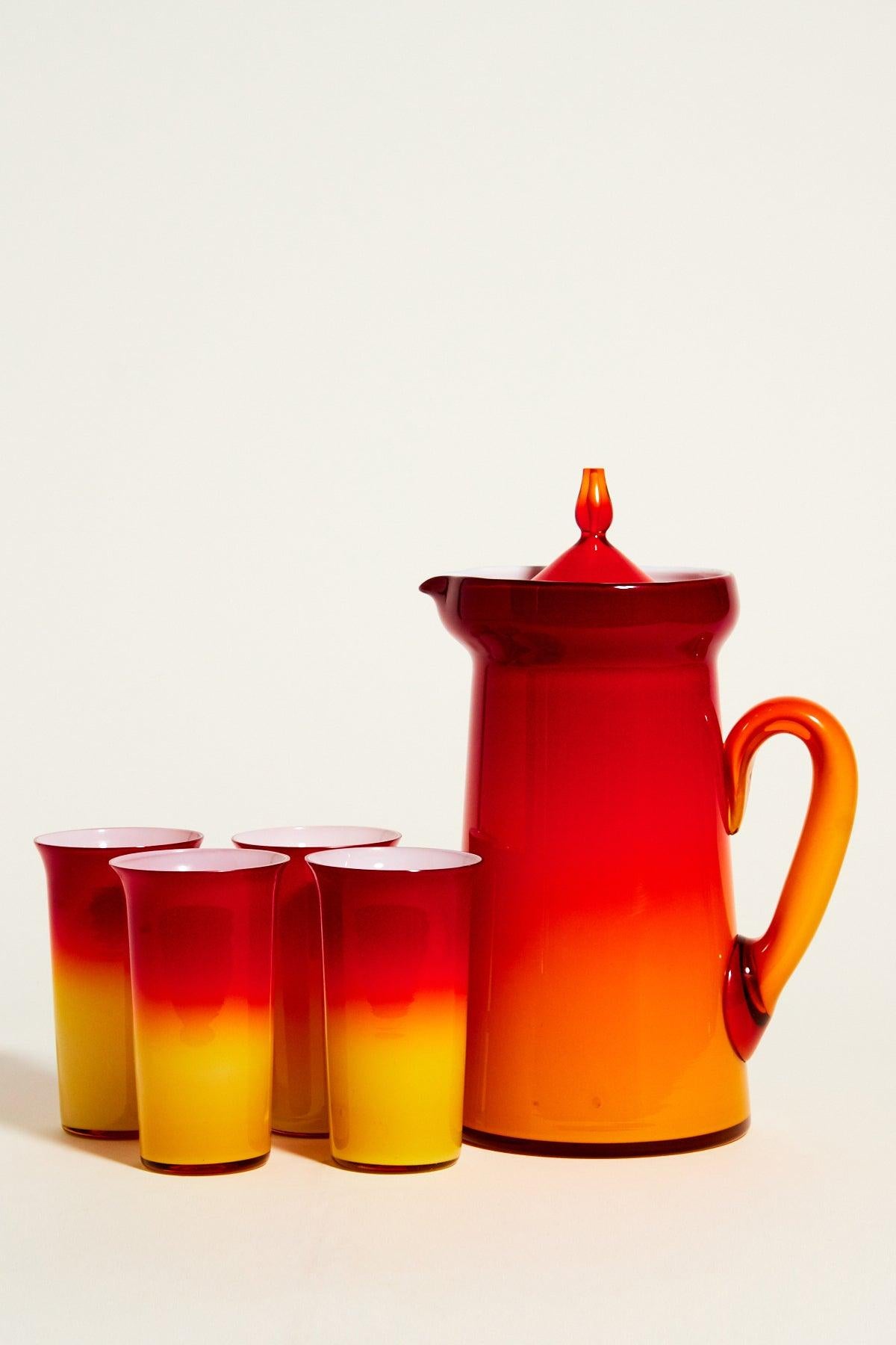 Brilliant ombré red and yellow layered glass pitcher set with white interiors and cute lid on the pitcher.