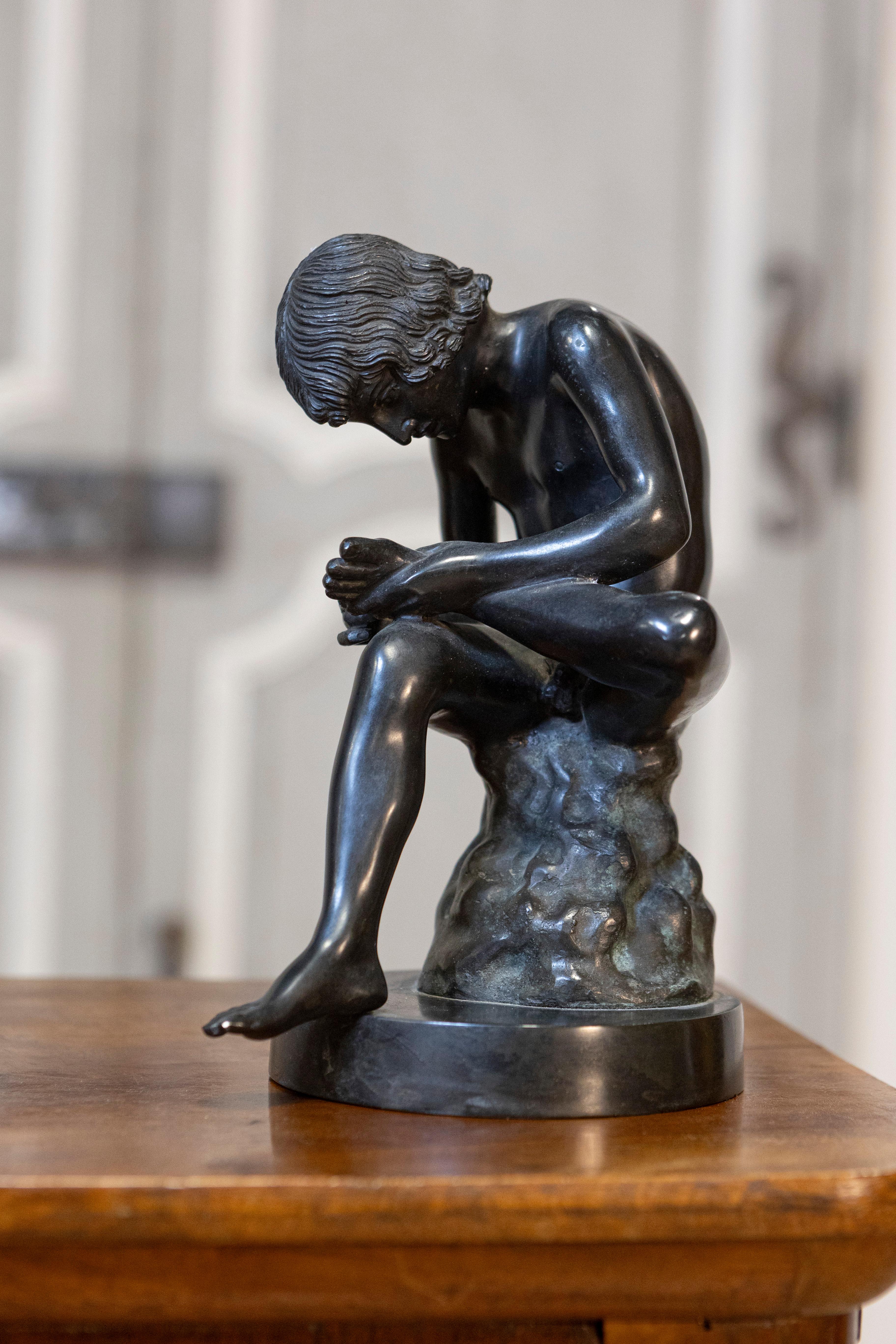 The Boy with the Thorn, Greco Roman style bronze statuette from the 20th century after the antique Spinario. This 20th-century bronze statuette, a contemporary interpretation of the classic Spinario, is a testament to the enduring allure of