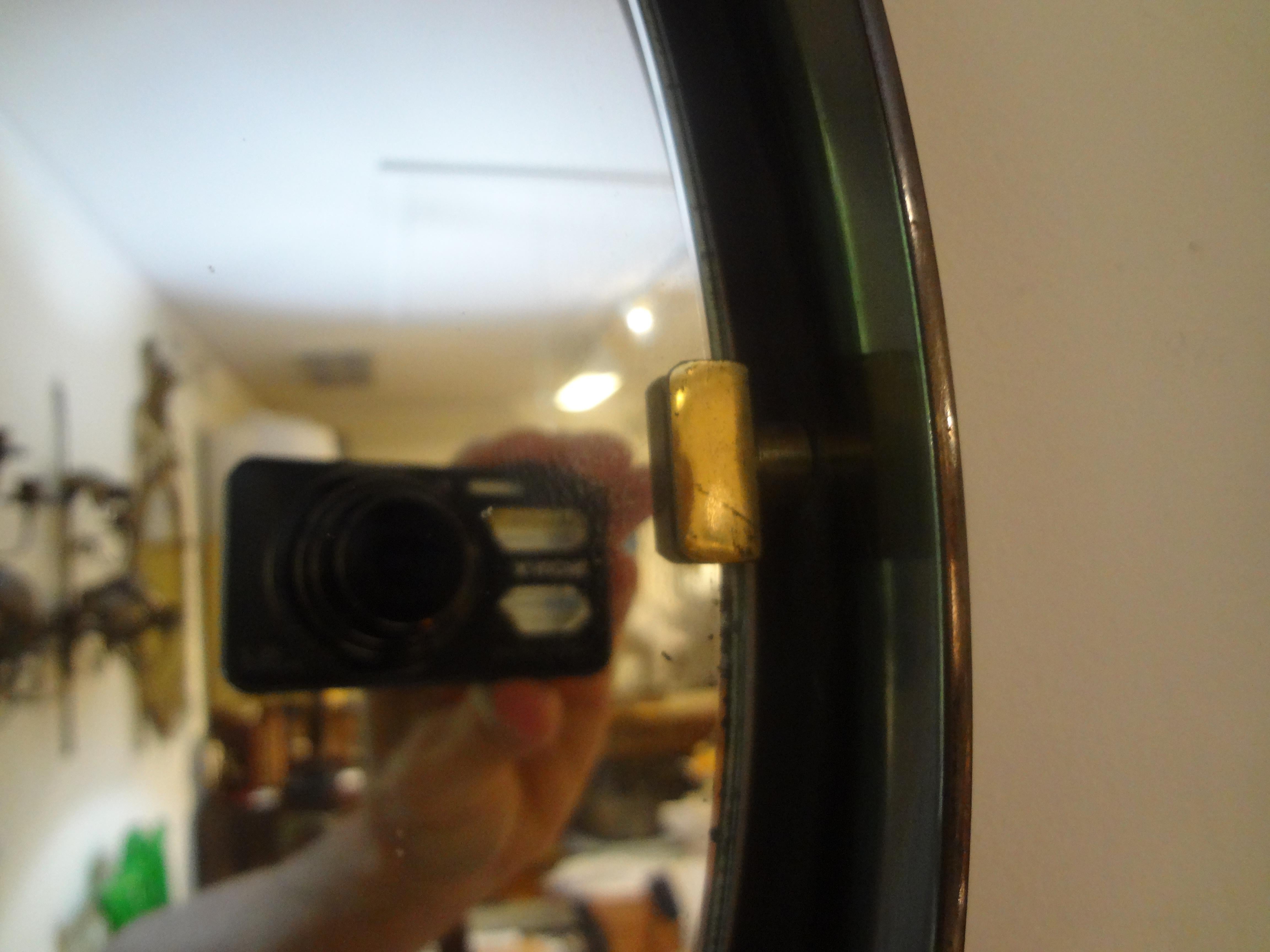Miroir italien en bronze et laiton. 
Ce miroir rond italien de style moderne du milieu du siècle est doté d'une structure en bronze et de ferrures en laiton qui maintiennent le miroir en place. Le miroir central donne une impression de flottement.
À