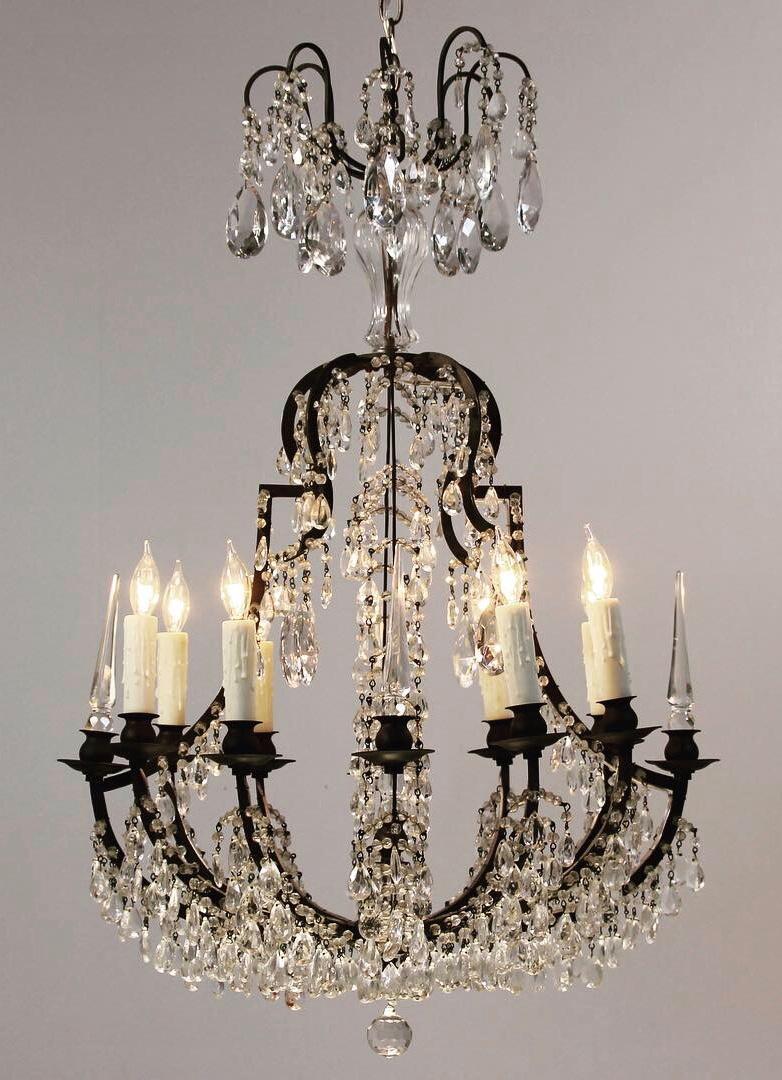 Graceful lines and an abundance of crystal prisms define this wonderful 1940s Italian Versailles-style chandelier. The chandelier consists of a bronze frame which has acquired a pleasing dark patina over the decades, hundreds of small crystal prisms