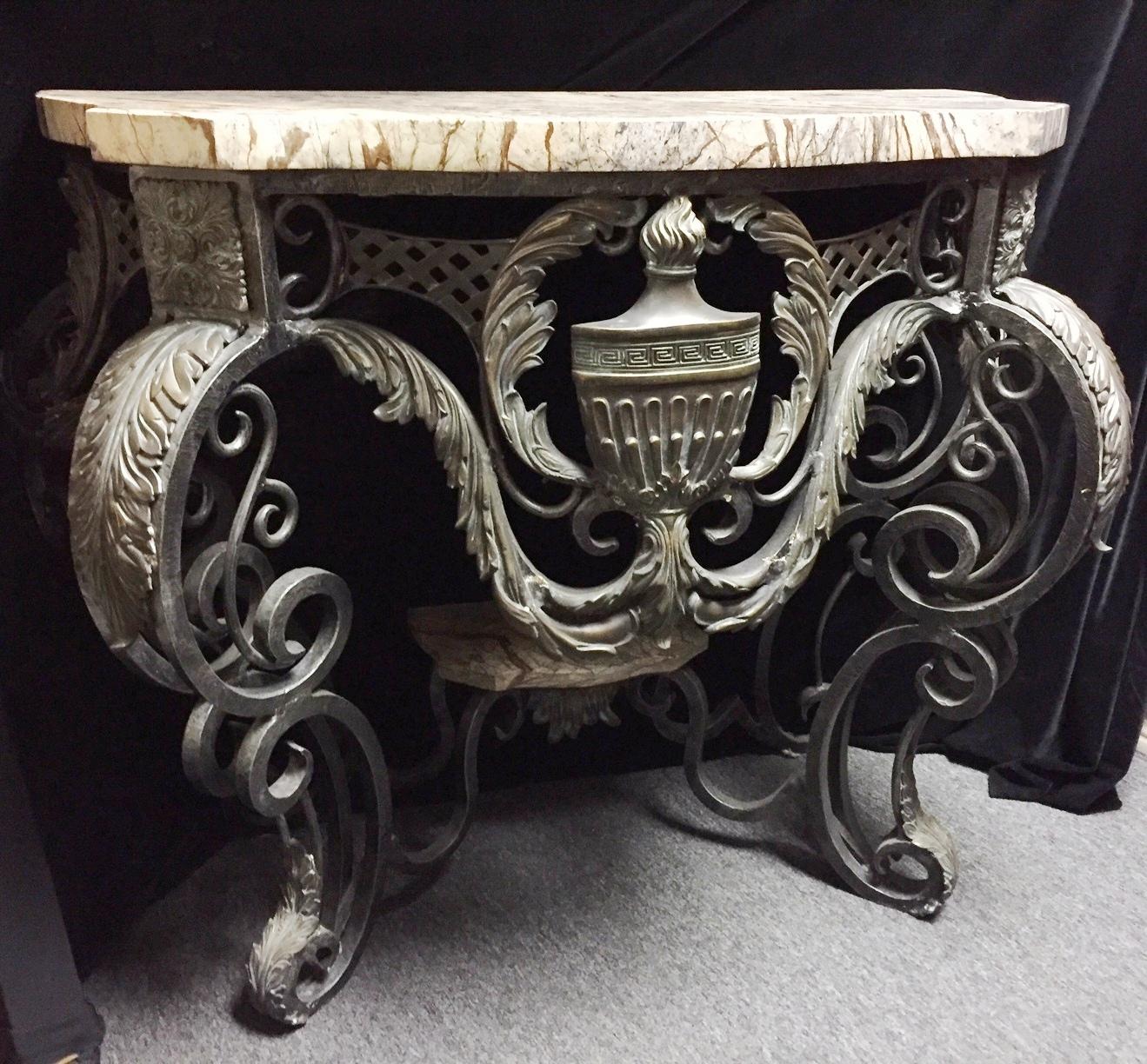 Attractive Italian Baroque style hand forged wrought iron and bronze console with thick marble tops centered with a bronze urn encased in a foliage cartouche and supported by four double scrolled legs mounted with bronze acanthus leaves and