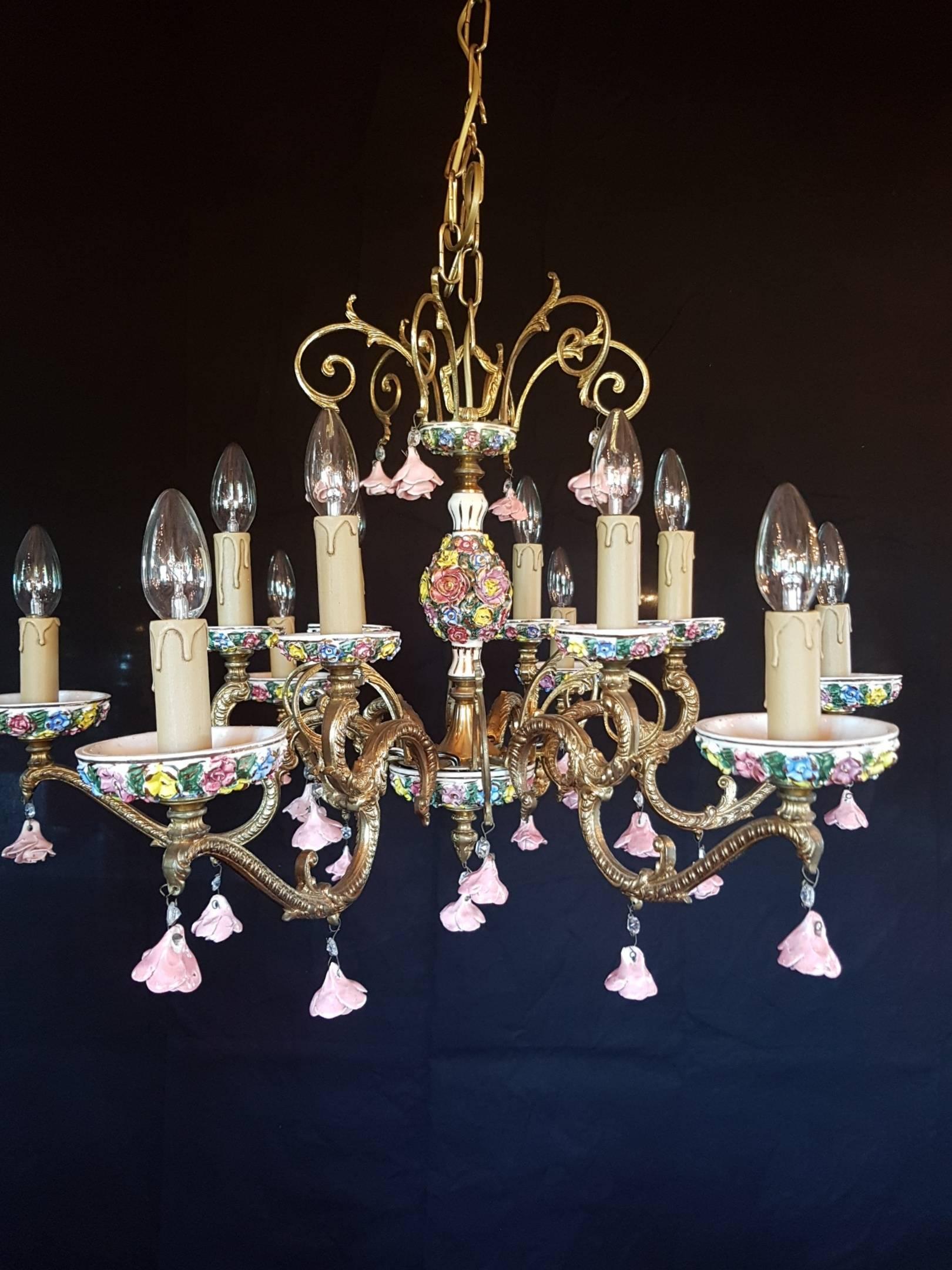 Italian bronze chandelier with bobeches and the vase in the central made of porcelain. The chandelier is decorated with tiny roses of porcelain. The colors are looking very nice. This chandelier has 12 candle lights.

This is just one of our large