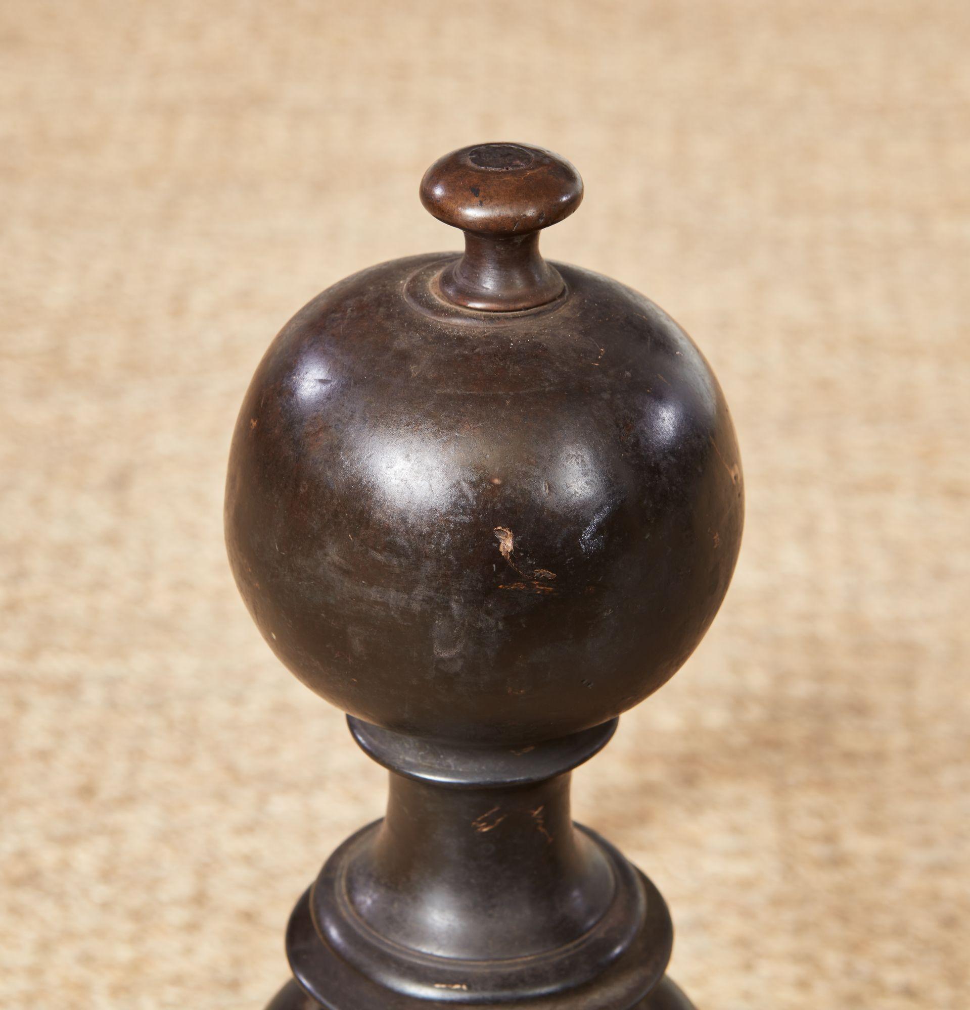 Paire de chenets en bronze d'époque, à la riche patine d'origine, chacun avec une boule et un fleuron sur une tige tournée en anneau, avec des plaques frontales en forme d'ailes patinées de la même façon, et des pieds arrière en fer forgé à la main.