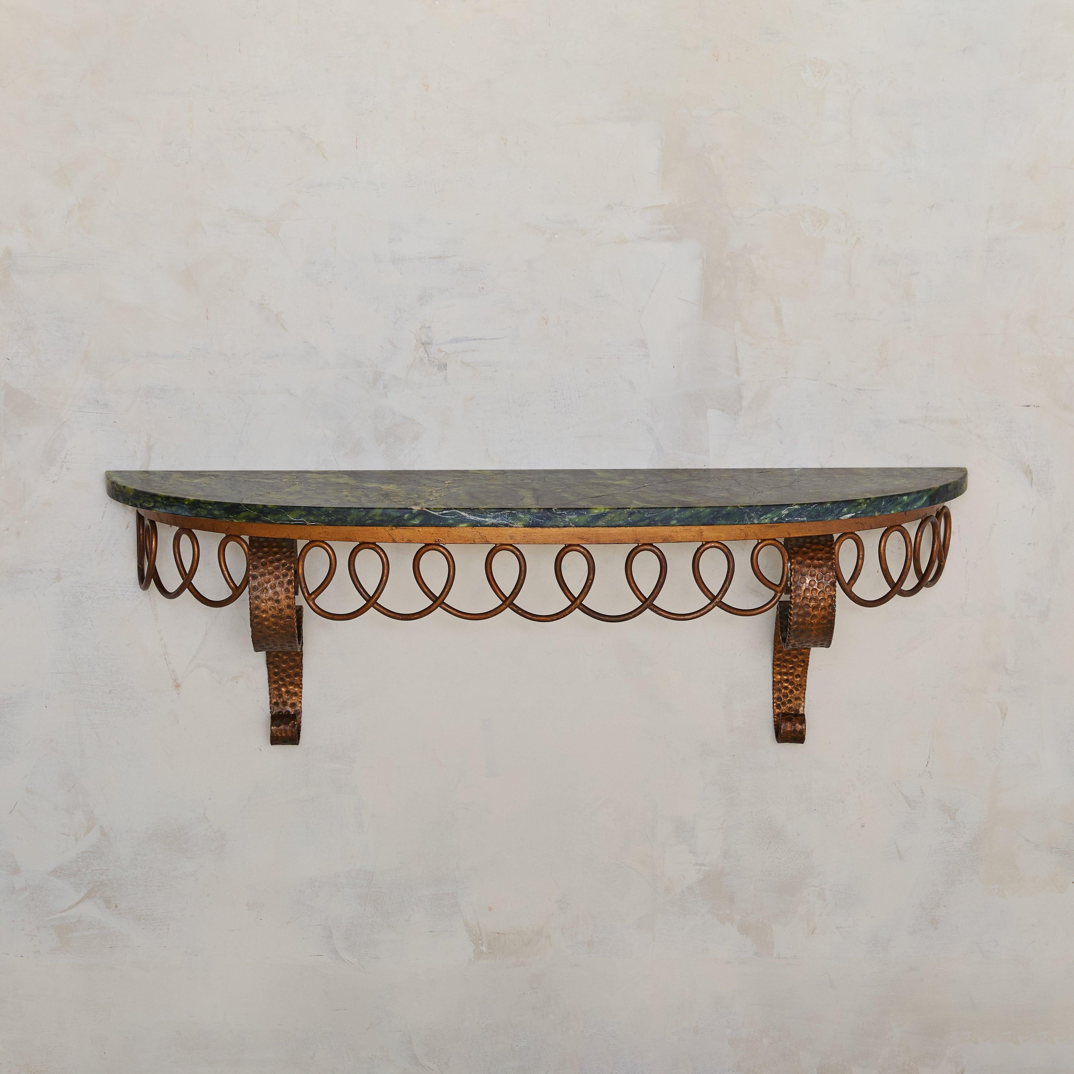 A 1950s Italian wall-mounted demilune console, featuring a richly veined honed marble top. The natural stone displays vibrant green tones with delicate ivory accents. The bronze base is adorned with intricate looping details and elegantly scrolled
