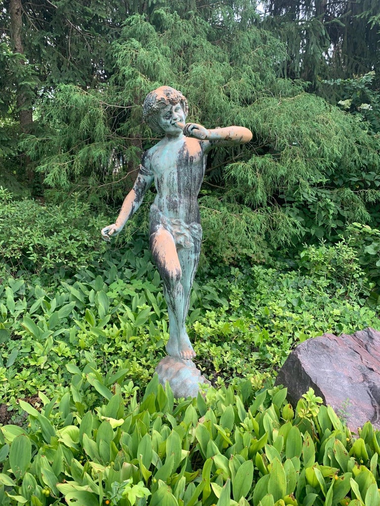 Antique Italian bronze & copper garden statue or sculpture of pan playing flute while standing on a conch shell on an oval plinth. From an estate with a world class garden, in the grounds of prominent St. Louis Country Club. Pan of Greek mythology