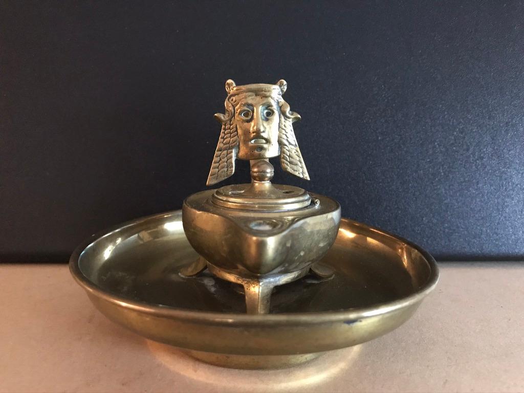 Grand tour oil lamp modeled after an ancient Roman original, decorated with a wonderful Greek inspired theater mask. The tripod lamp, with hinged lid, is set into a low footed dish. I have handled hundreds of Grand Tour pieces over the years and