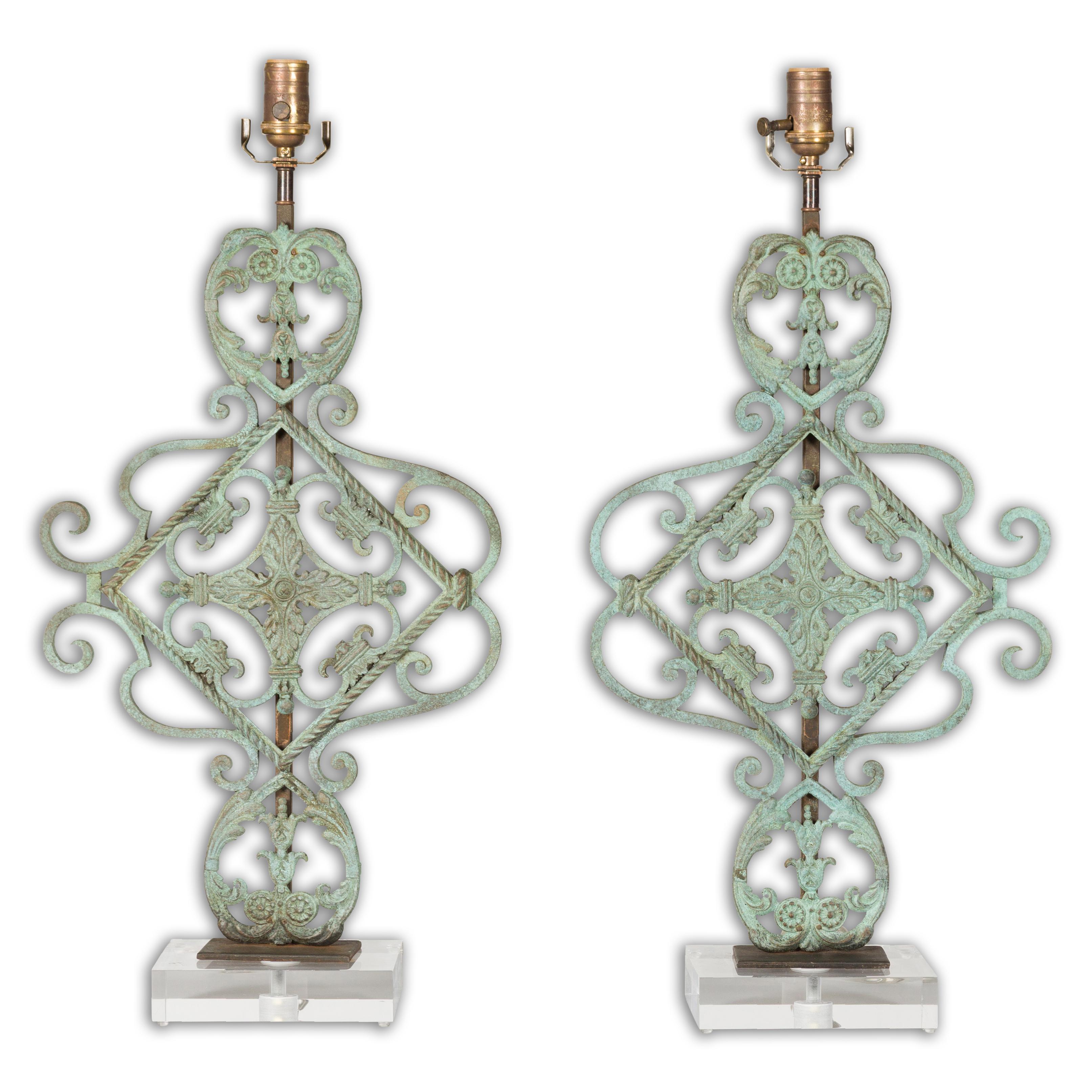 A pair of Italian Midcentury bronze table lamps with scrolling motifs, foliage, verdigris patina and custom made rectangular lucite bases. Illuminate your interiors with a blend of elegance and style, featuring this pair of Italian Midcentury bronze