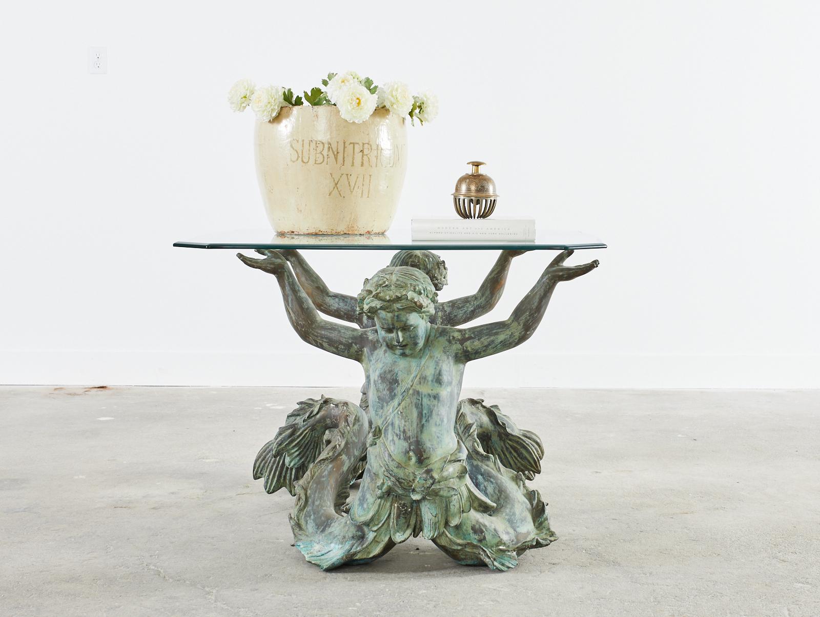 Exceptional Italian bronze center table featuring a pair of mermen or putti di mare. The bronze has a lovely patinated finish with verdigris. The base alone measures 45 inches wide by 30 inches deep depicting two mermen back to back with