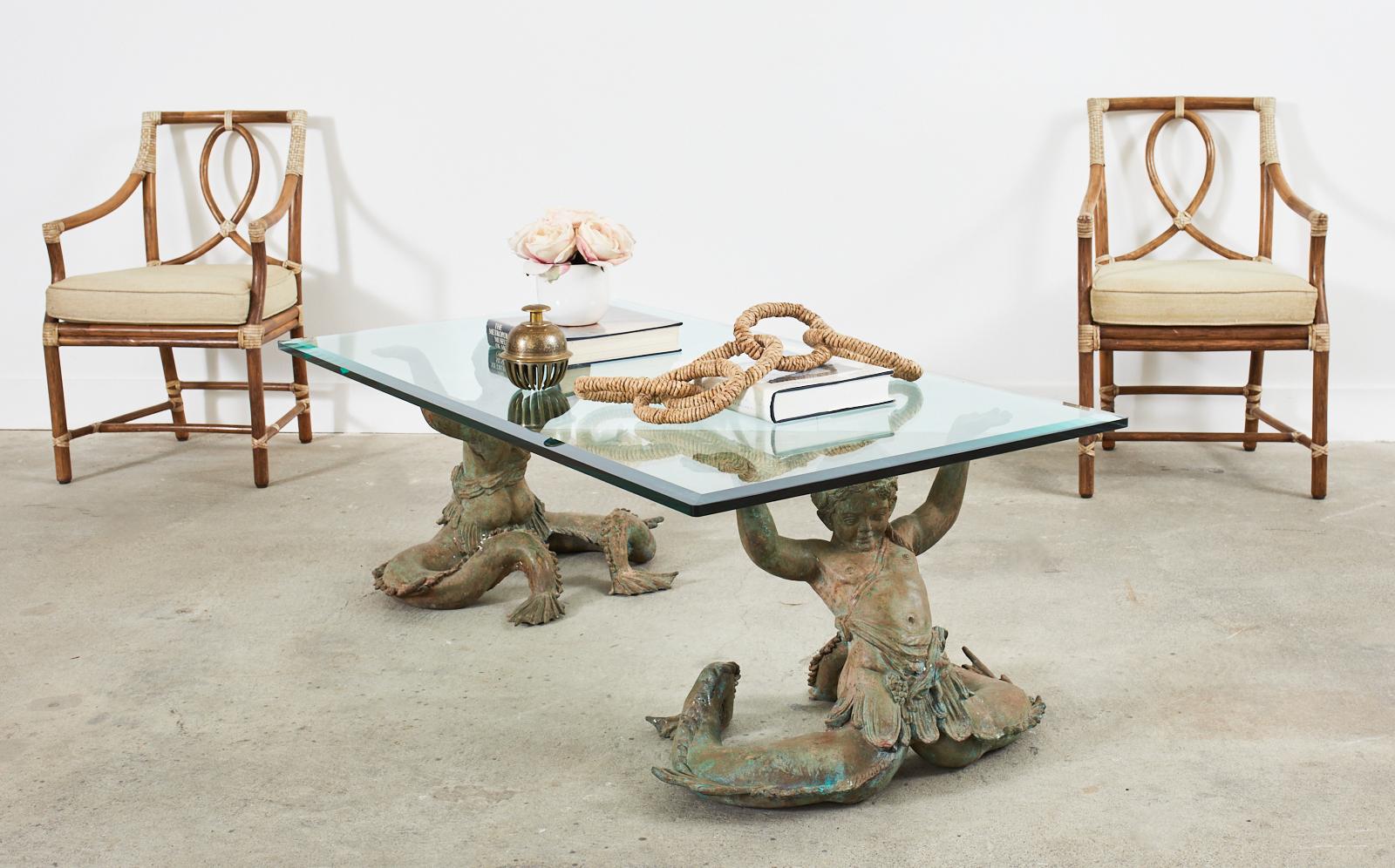 Fantastic Italian nautical cocktail table or coffee table featuring a pair of patinated bronze Putti Di Mare mermaids supporting a thick glass pane. The mythical grotto style cherub mermaids are unattached which is very unique as most of these pairs