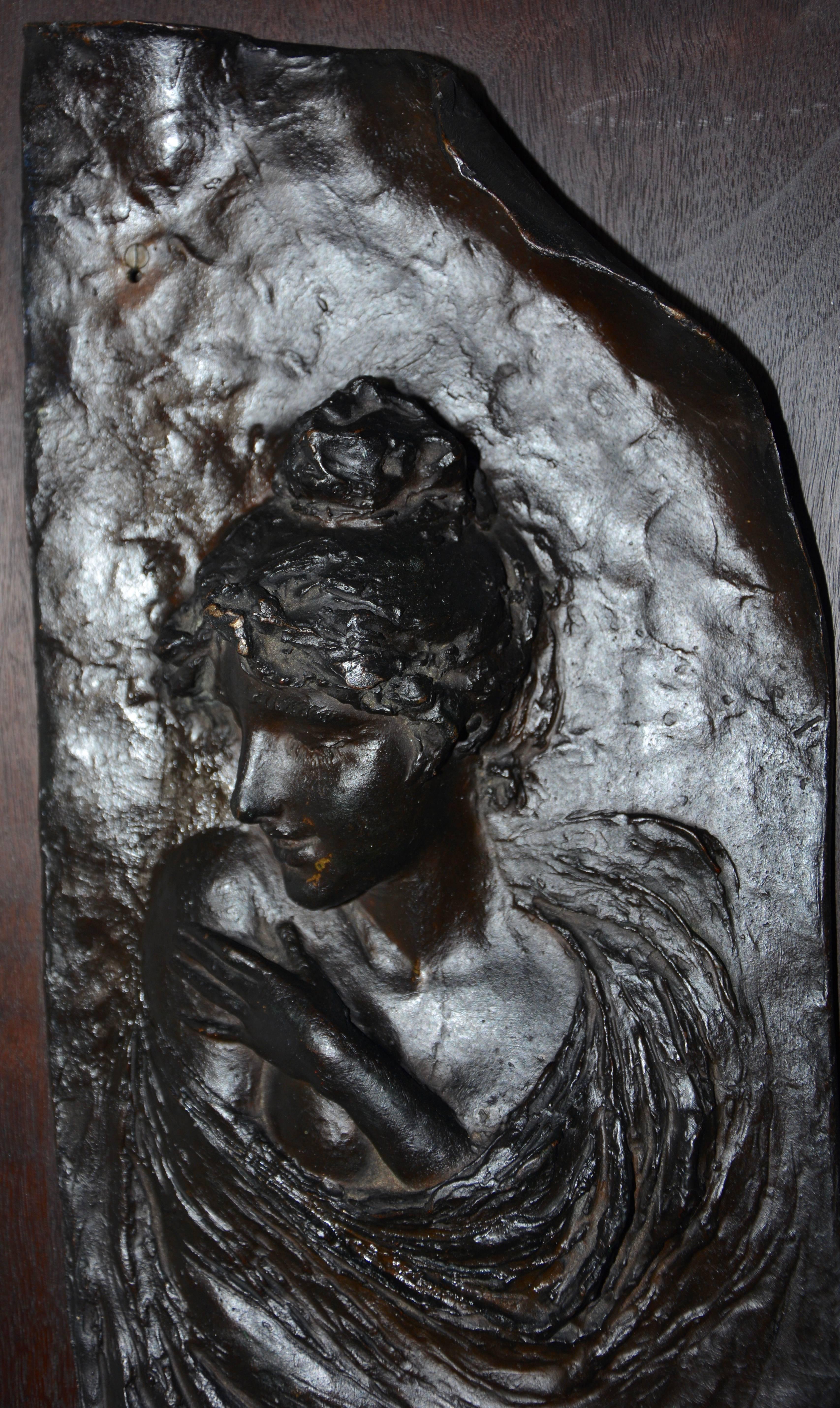 Beauty flows from this bronze of a lady mounted on a wooden plaque. It is marked 