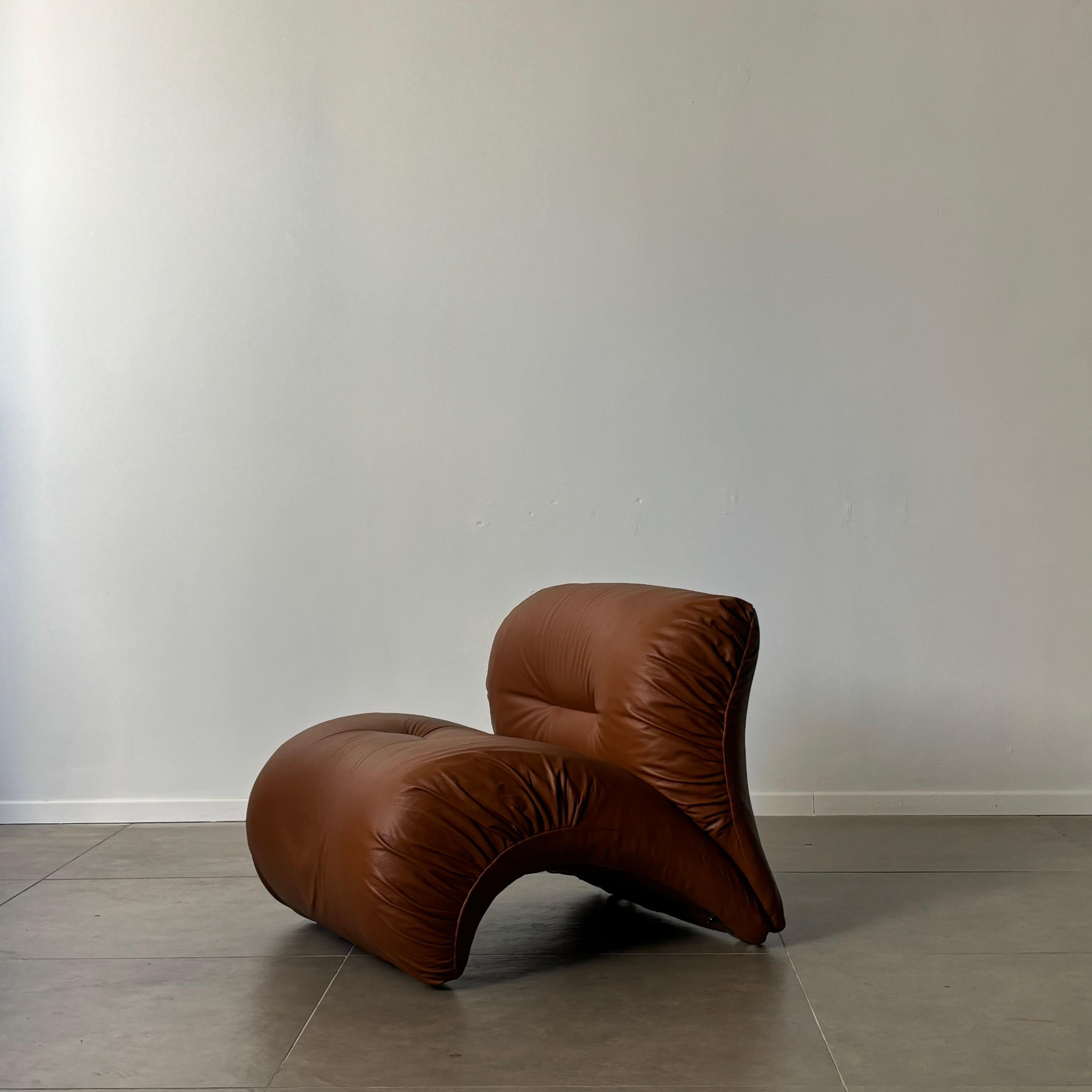 This exquisite Italian armchair from the 1970s is a testament to the era's innovative design and attention to detail. The chair features a beautifully arched seat that effortlessly cradles the sitter, complemented by a plush, puffy backrest that