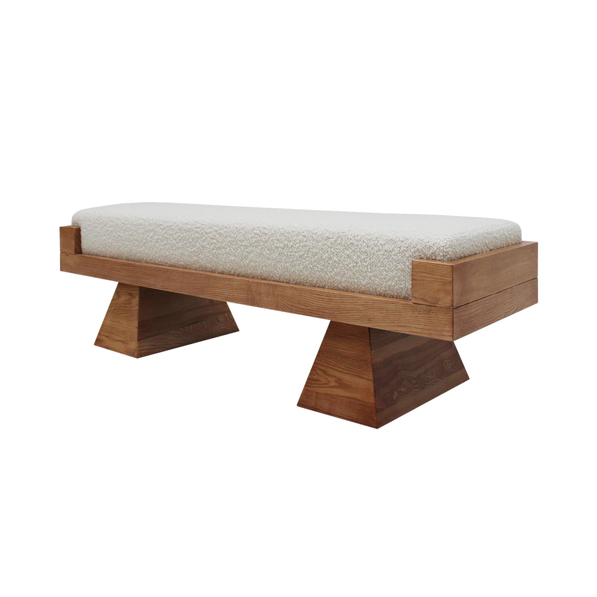 Contemporary Italian bench in a striking Brutalist style, featuring sculptural, architectural lines. The piece consists of two truncated pyramid-shaped bases in solid oak supporting a seat upholstered in high-quality wool bouclé. Combining