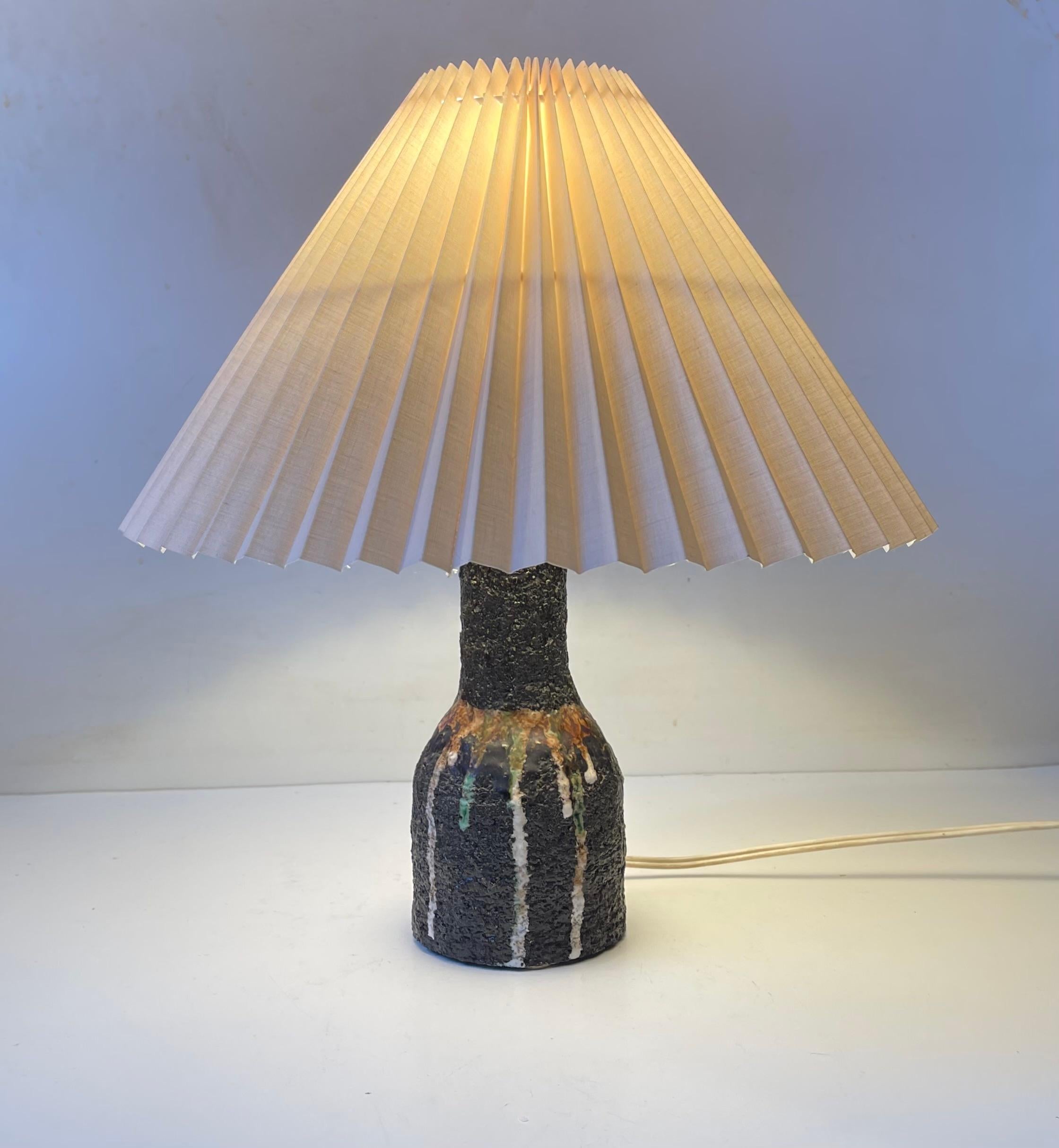 Lampe de table italienne d'aspect brut exécutée dans un type d'argile chamottée avec des glaçures à gouttes coulantes en vert clair, blanc et brun. Fabriqué par un studio en Italie vers 1970-75. Elle est montée avec un abat-jour en acrylique