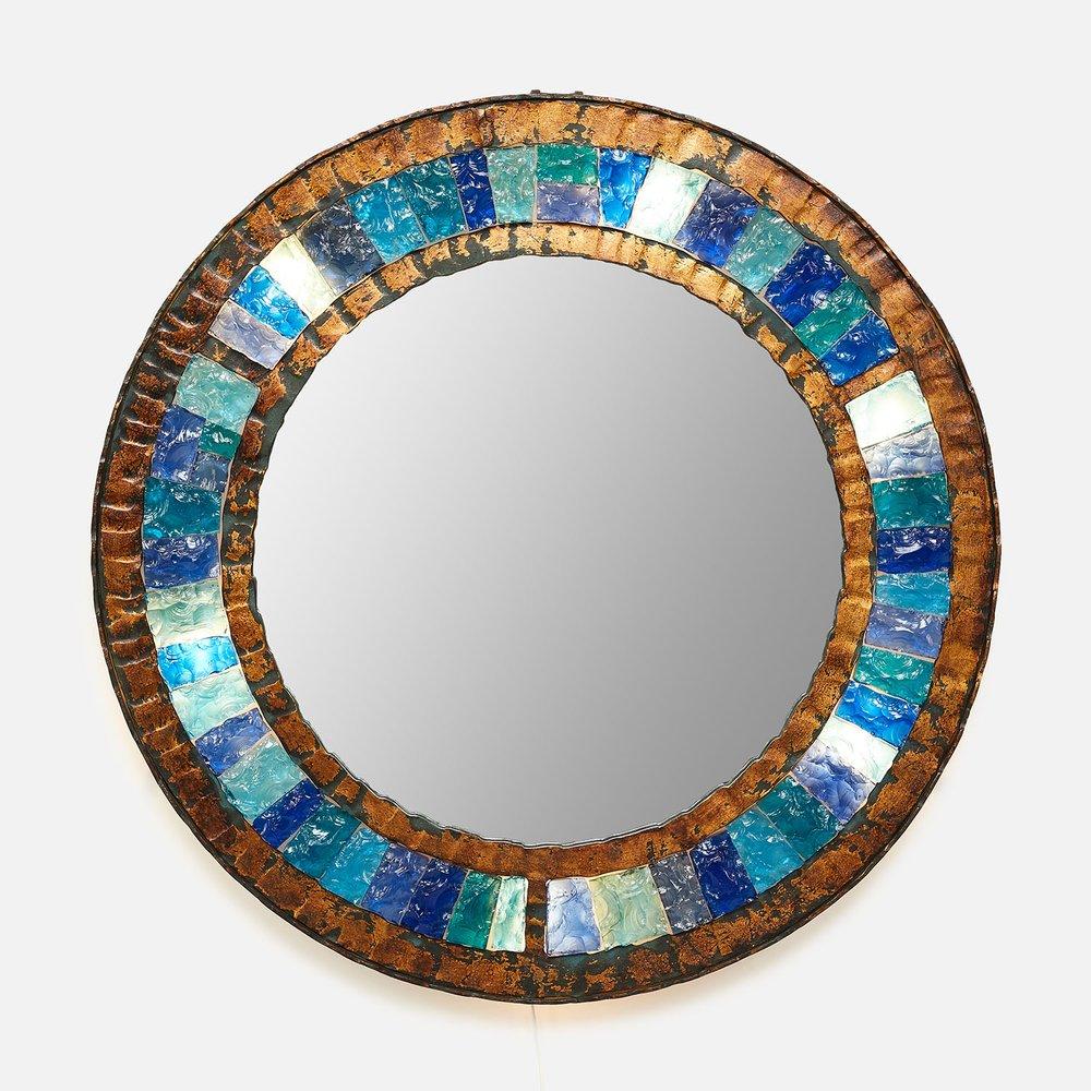 Italian brutalist illuminated wall mirror
Italy, circa 1970’s
Gilt hand-hammered iron frame 
Original chip-carved colored glass
Beautiful color palette ranging from deep blues to lighter turquoise highlights
Patina from age and use
Newly rewired
