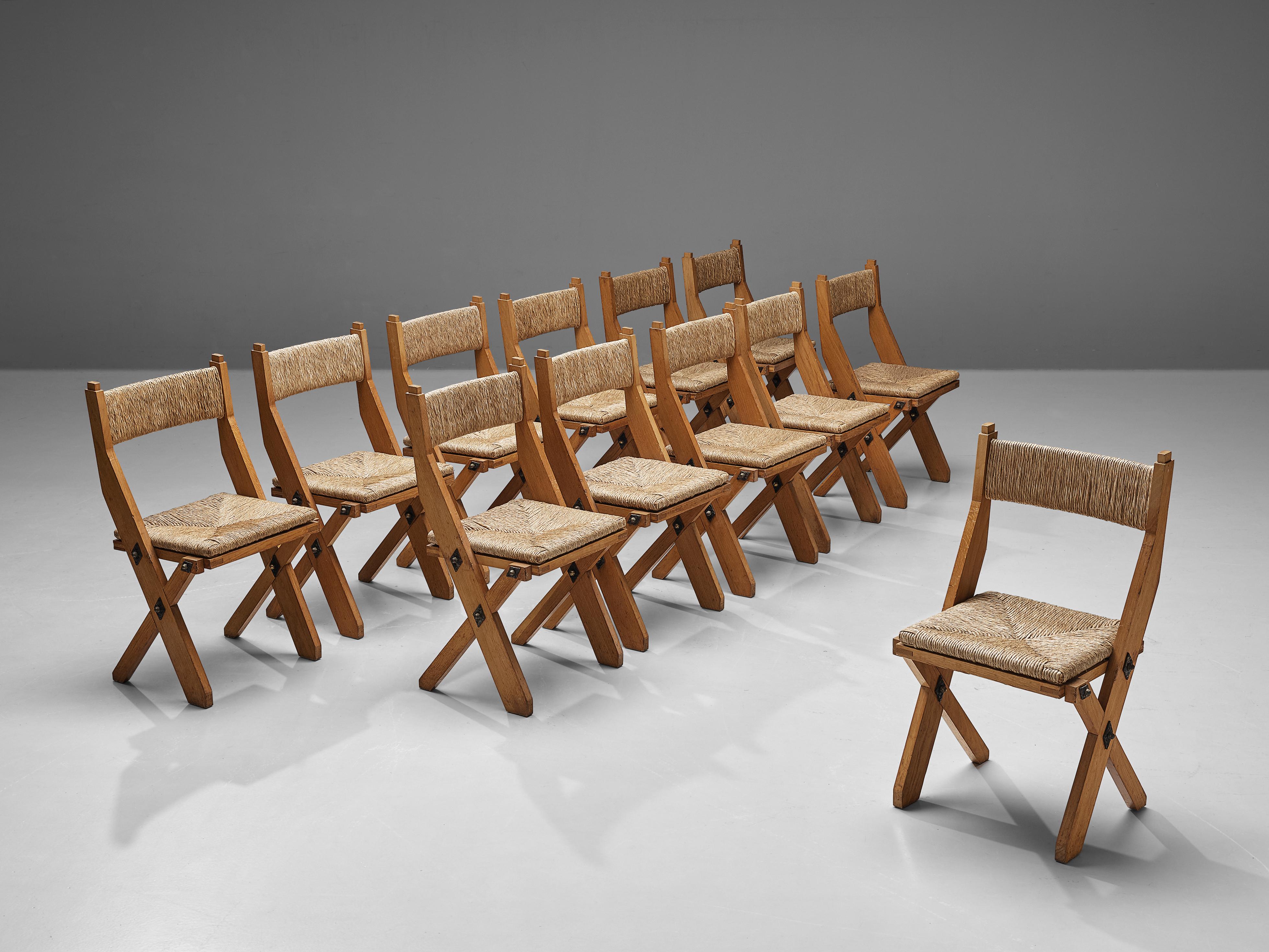 Dining chairs, oak, metal, brass, straw, Italy, 1970s.

Brutalist set of twelve chairs from Italy with a strict, sturdy design. The chairs are executed in thick slats of oak wood. The seat is made of straw and combines beautifully with the oak