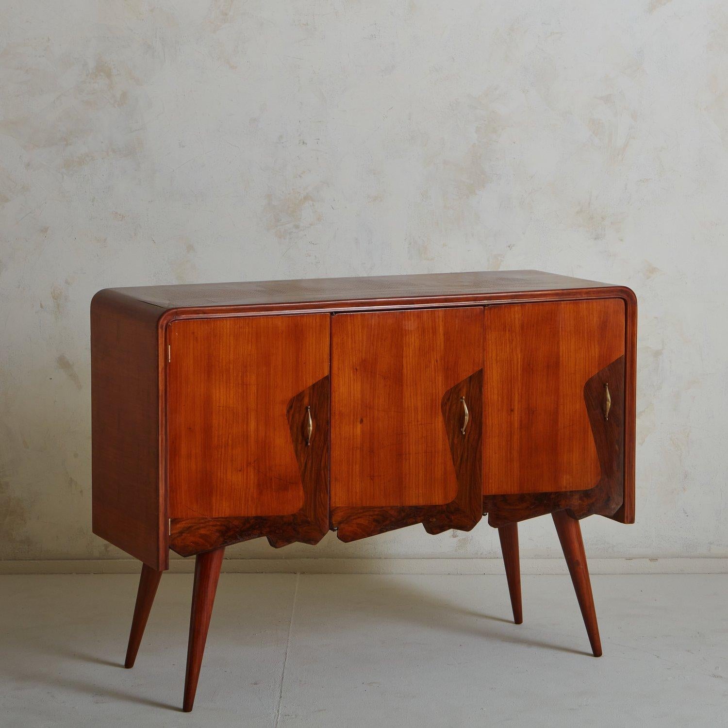 A handsome 1960s Italian credenza constructed with cherry wood. This piece has three doors with inlaid burl wood detailing and brass hardware. It stands on tapered, angled legs. Retains ‘Giuseppe Galli & Figli S.R.L. Mobili’ label en verso. Sourced