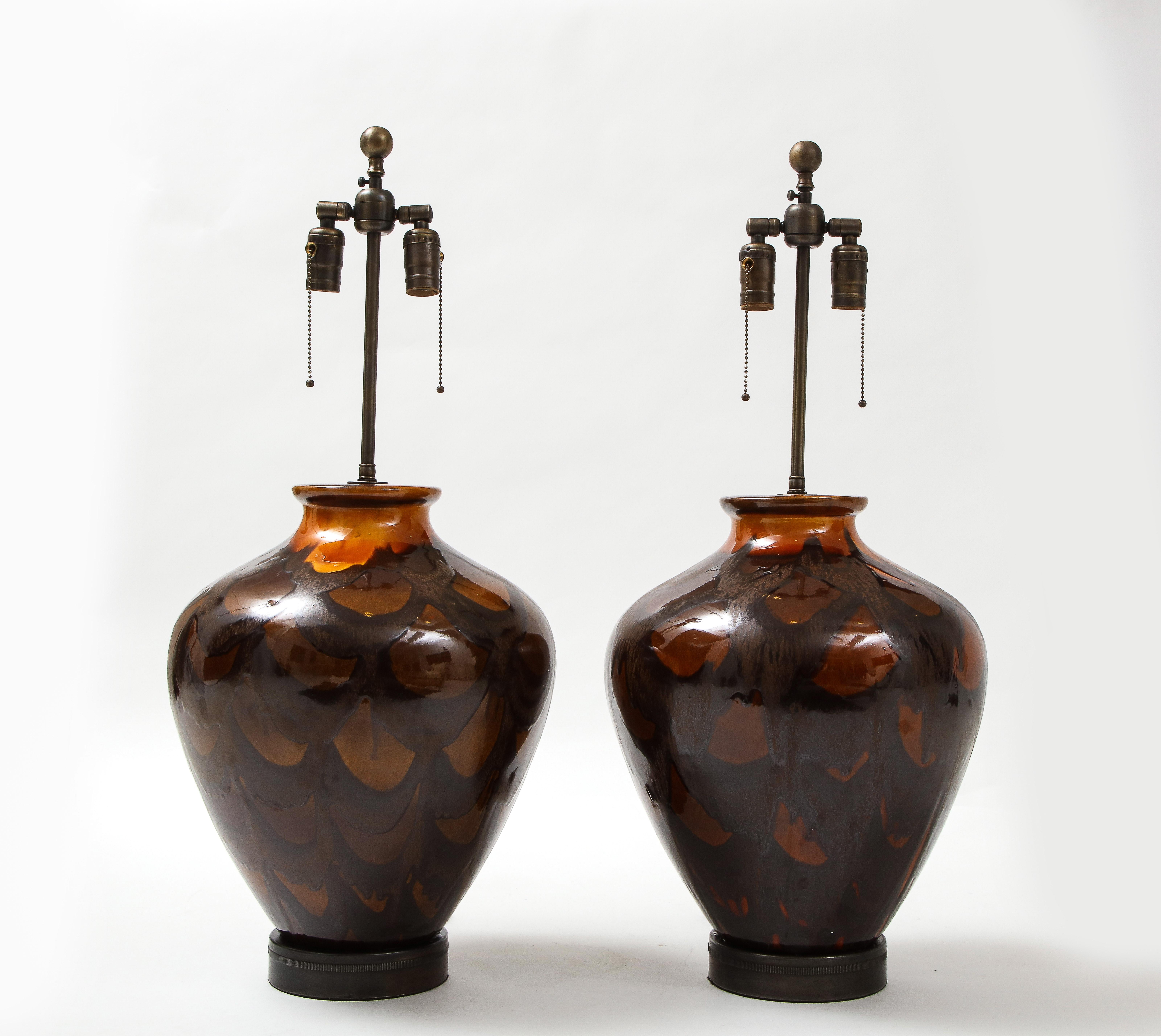 Pair of large scale modernist Italian pottery lamps with a stylized tortoise shell, burnt orange glaze. Lamps sit on aged bronze bases and feature double pull chain sockets. 75W max each socket.