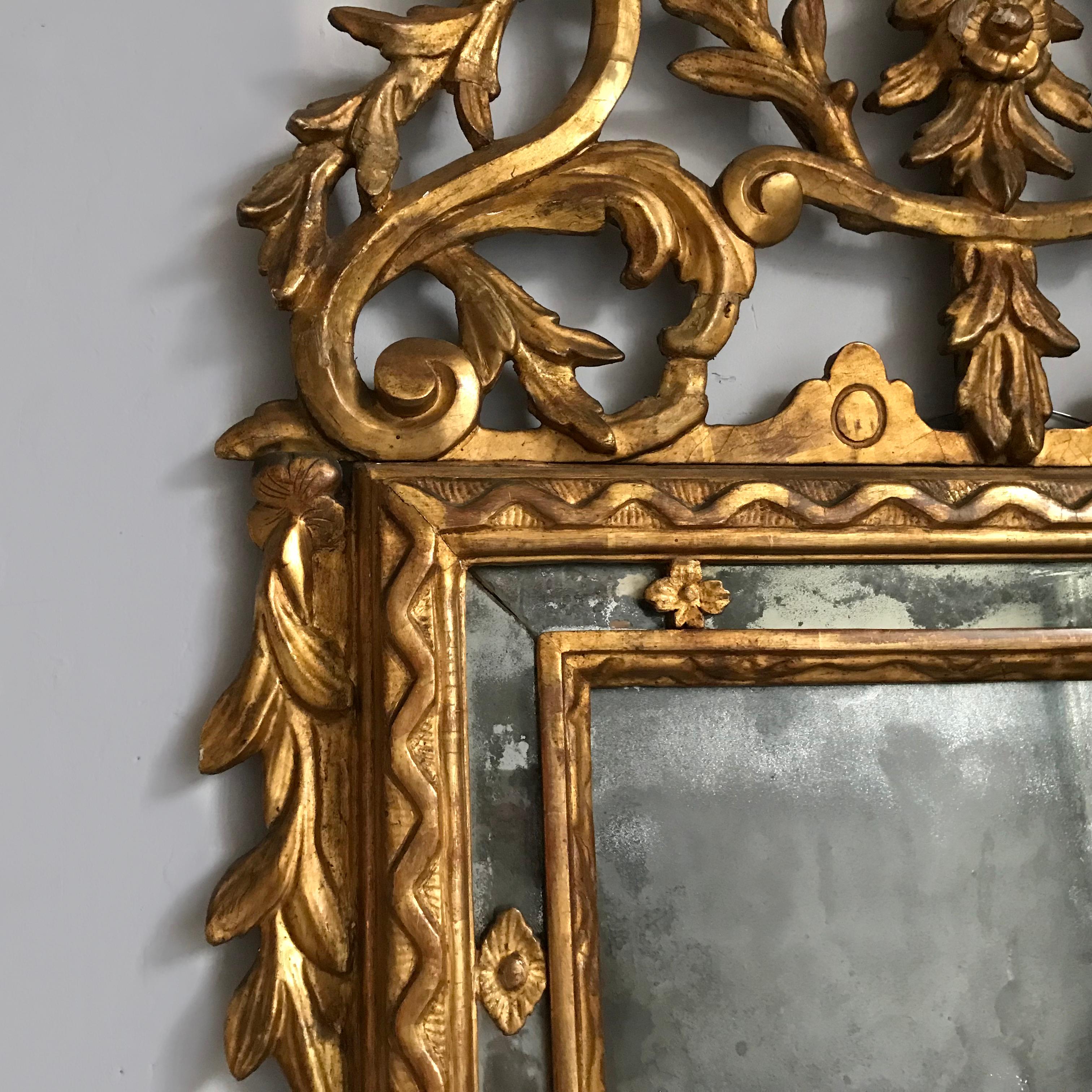 Ce miroir en bois doré d'Italie du Nord, datant de la fin du XVIIIe siècle, a étonnamment conservé sa plaque de verre au mercure d'origine, merveilleusement rouillée, dans un cadre en miroir entouré d'une sculpture continue en zigzag. Le tablier et