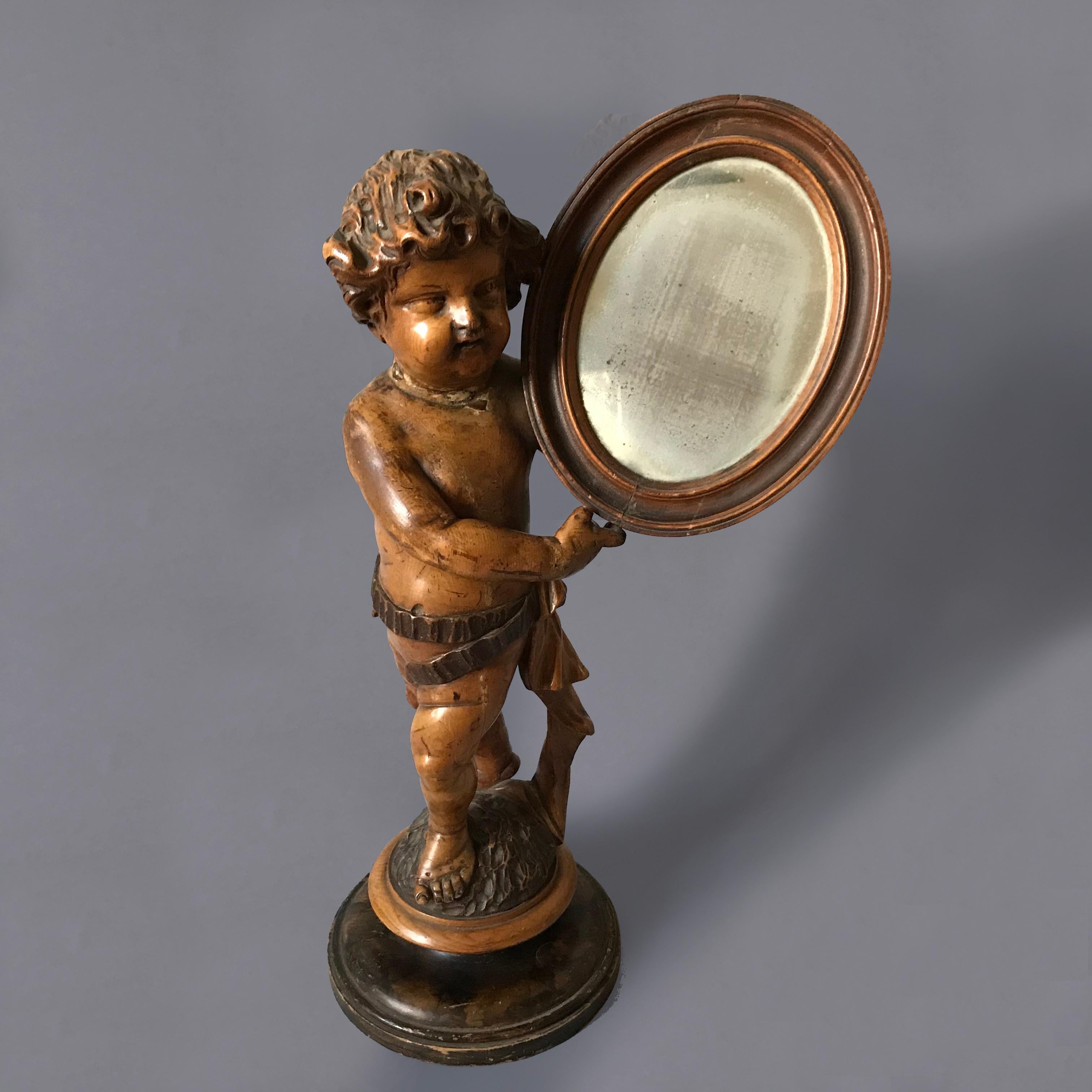 Beautifully carved Italian mid-C19th limewood cherub, or putto, holding a mirror with its original wonderfully foxed plate.