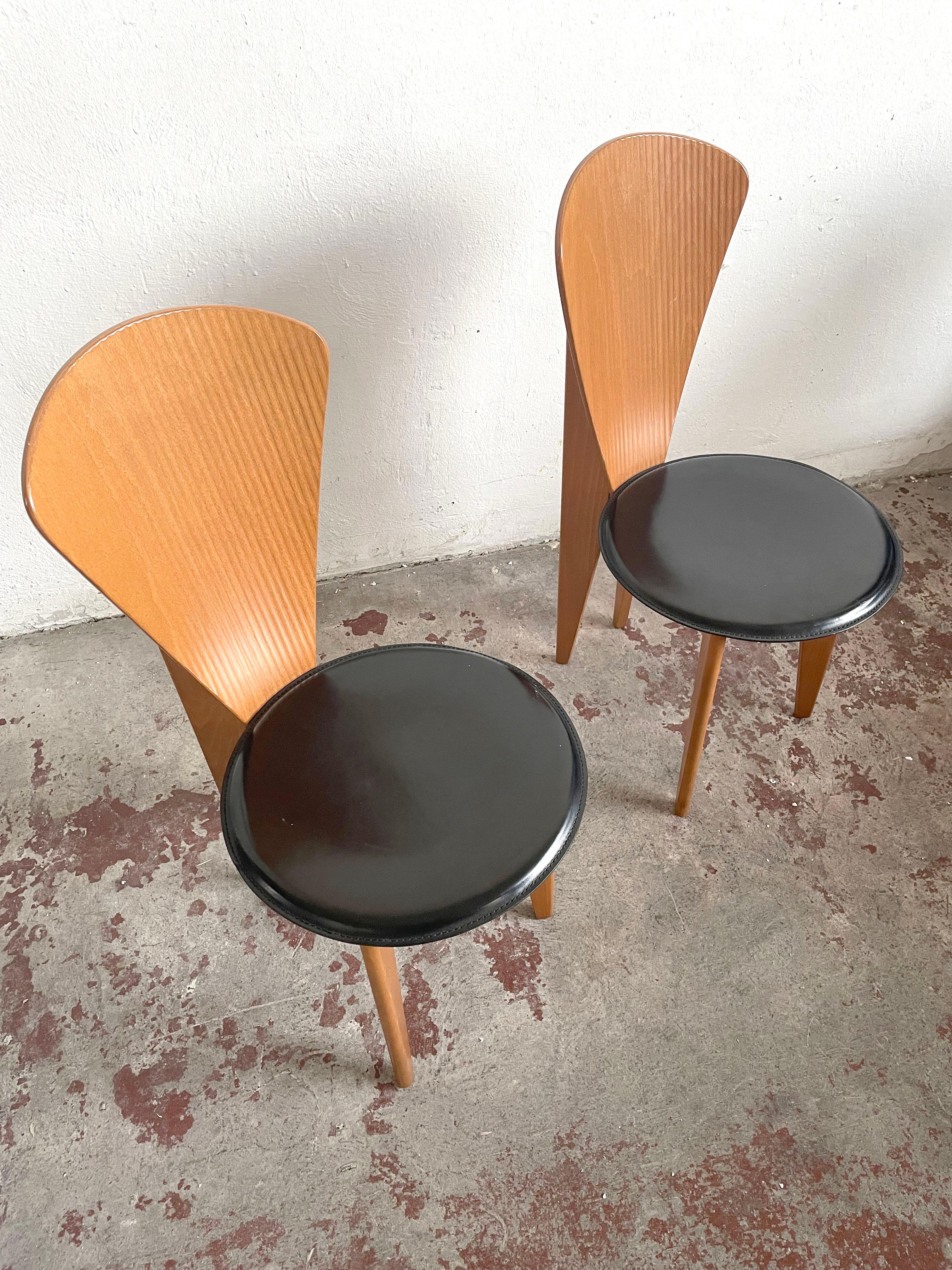 This set of two wooden dining chairs by Calligaris was made in Italy, circa 1980.

Stunning sculptural postmodern design. These dining chairs feature a curved back with ridges and round leather seats.

There are no structural issues. The leather