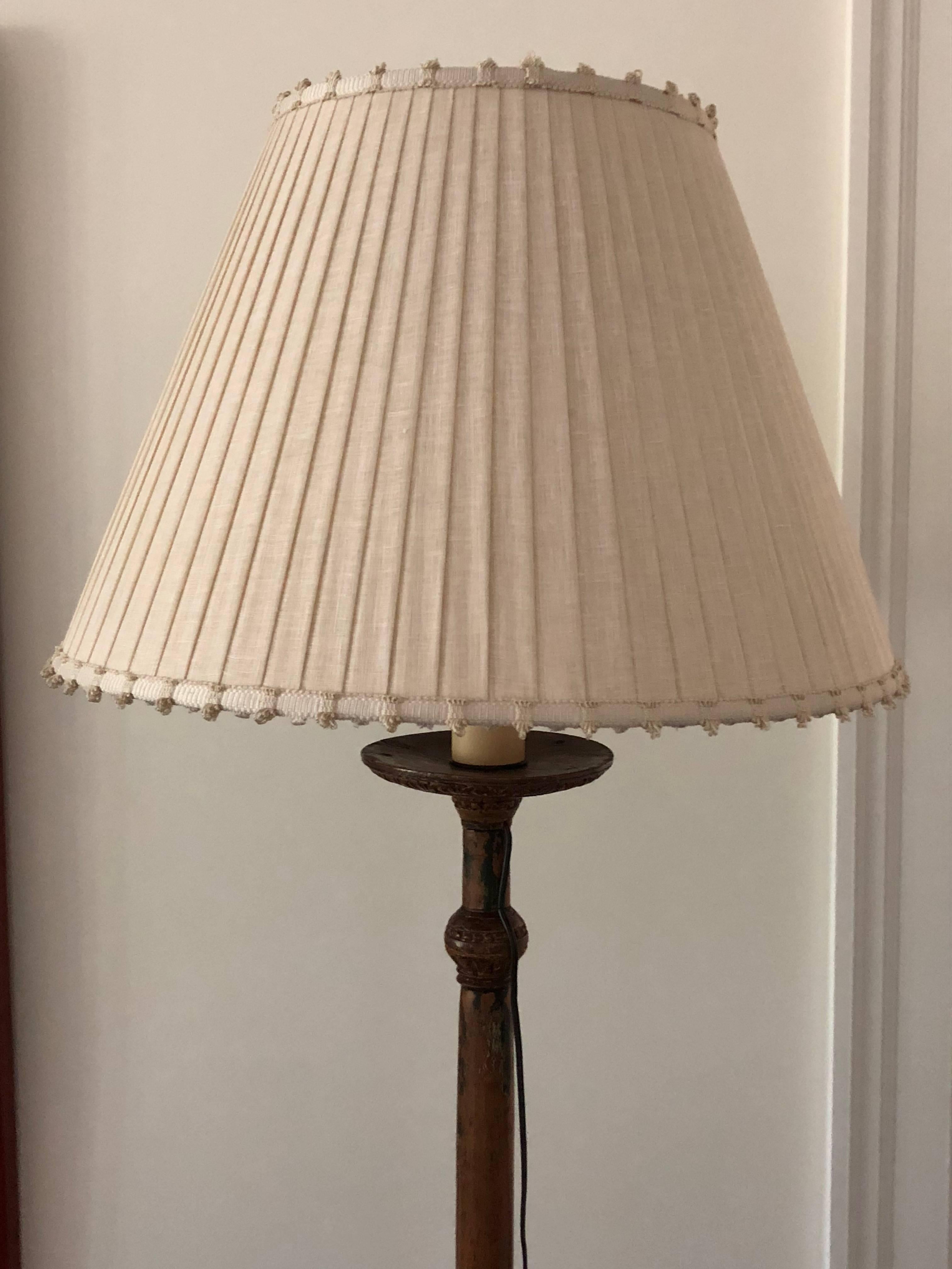 This Italian handmade, crafted, carved and painted wooden candlestick is gilded and mounted as a floor lamp well done hand-turned and three legged once being a torchiere and lacquered.