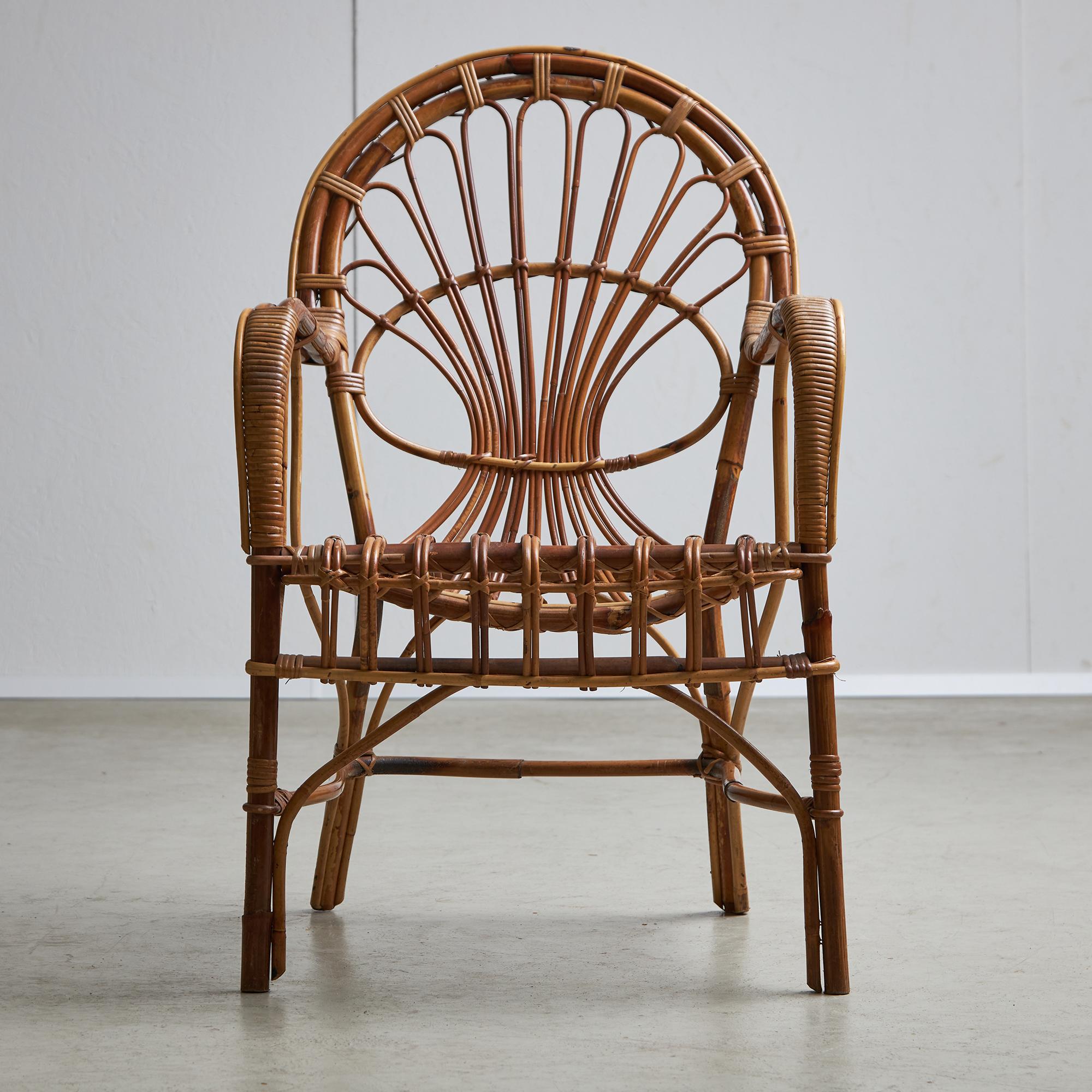 Enjoy the charm of la dolce vita with this Italian cane armchair, a piece that combines vintage style with lasting appeal. The chair has a unique round backrest and gently curved armrests, decorated with unique designs that show the skill of Italian