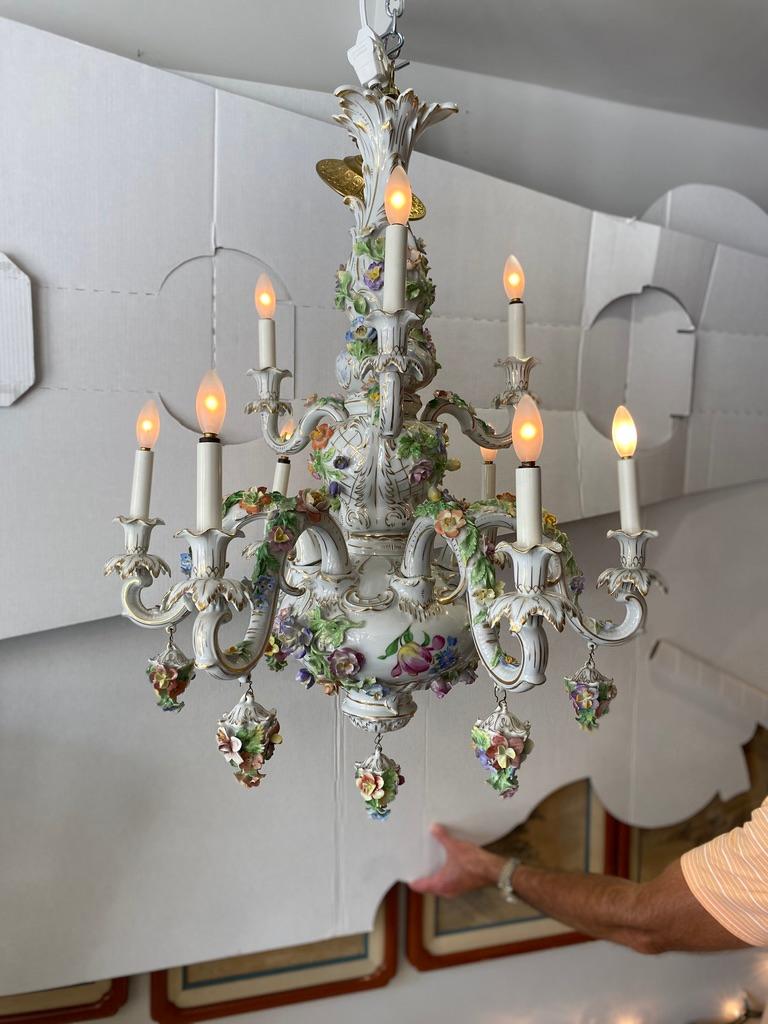 Italian CapoDiMonte chandelier handcrafted, hand painted Rococo porcelain having 2 tiers with 9 lights Three lights to the top tier and six to the bottom. Flower baskets on the bottom level. As fancy trim to complete with unusual chandelier, late