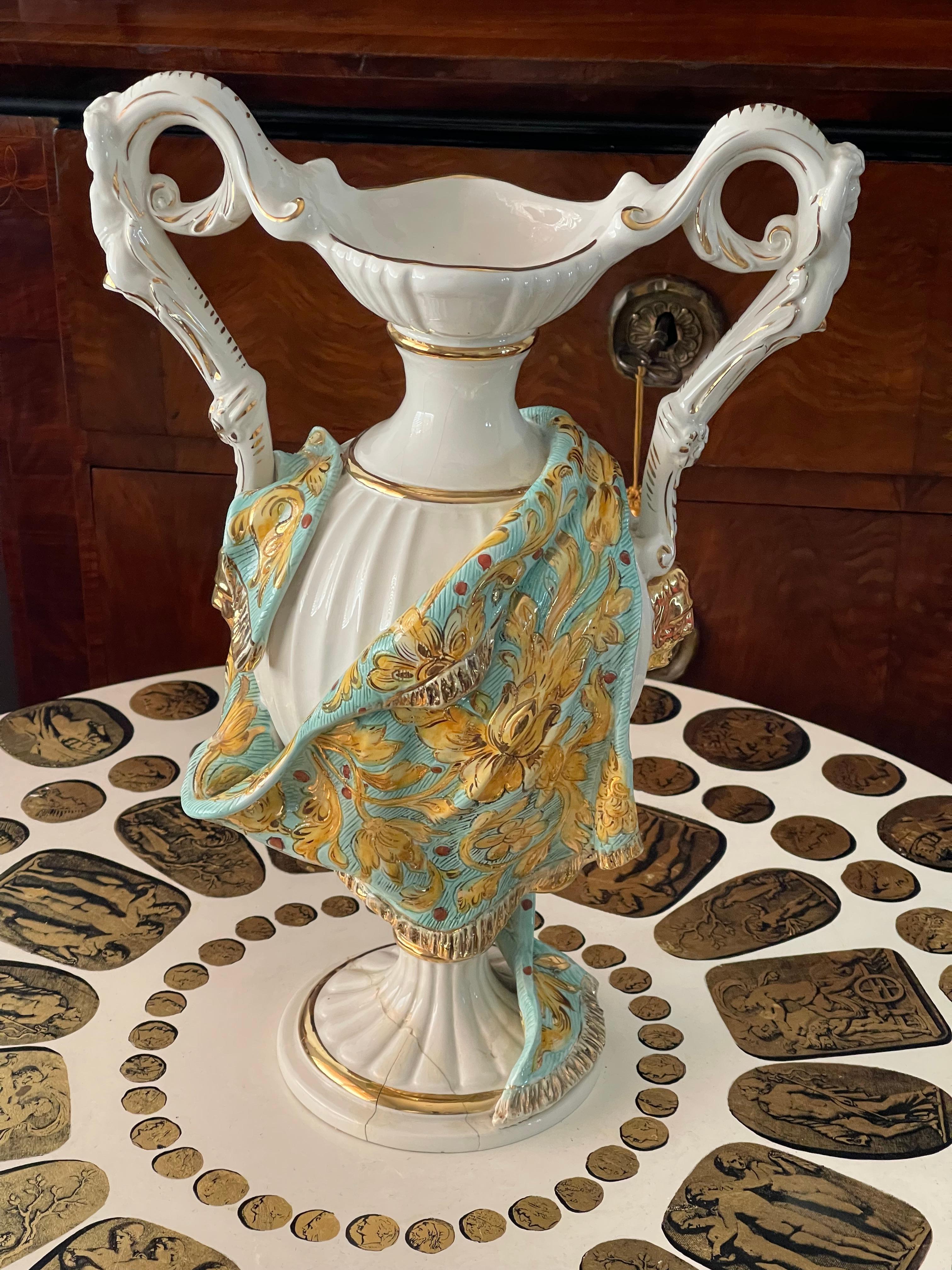 Impressionante vaso antico italiano di Capodimonte con manici a forma di cherubini e teste di leone dorate ai lati. Dipinto a mano in blu e oro. I danni alla base aggiungono carattere e sono considerati nel prezzo.