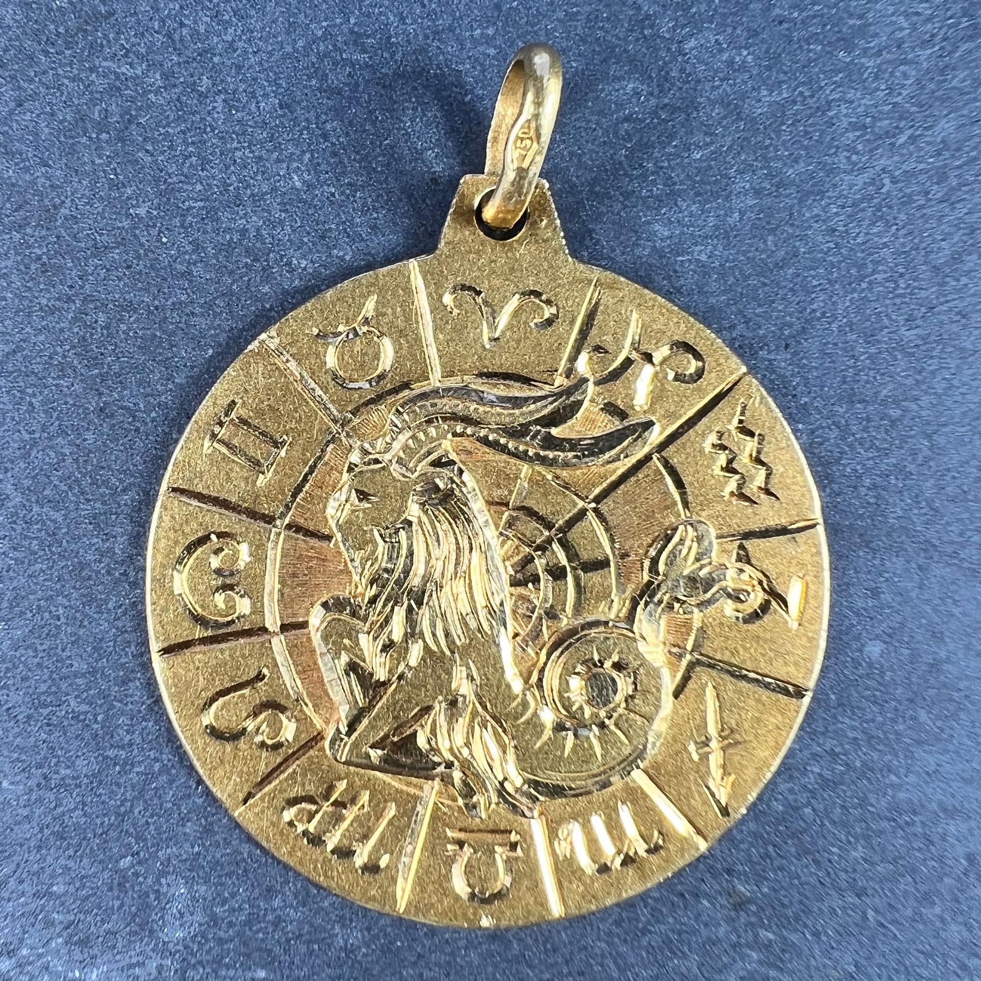 An 18 karat (18K) yellow gold charm pendant designed as a circular medal of the Zodiac starsign for Capricorn, surrounded by a frame depicting the symbols of the other Zodiac starsigns. Stamped with the owl mark for 18 karat gold and French import