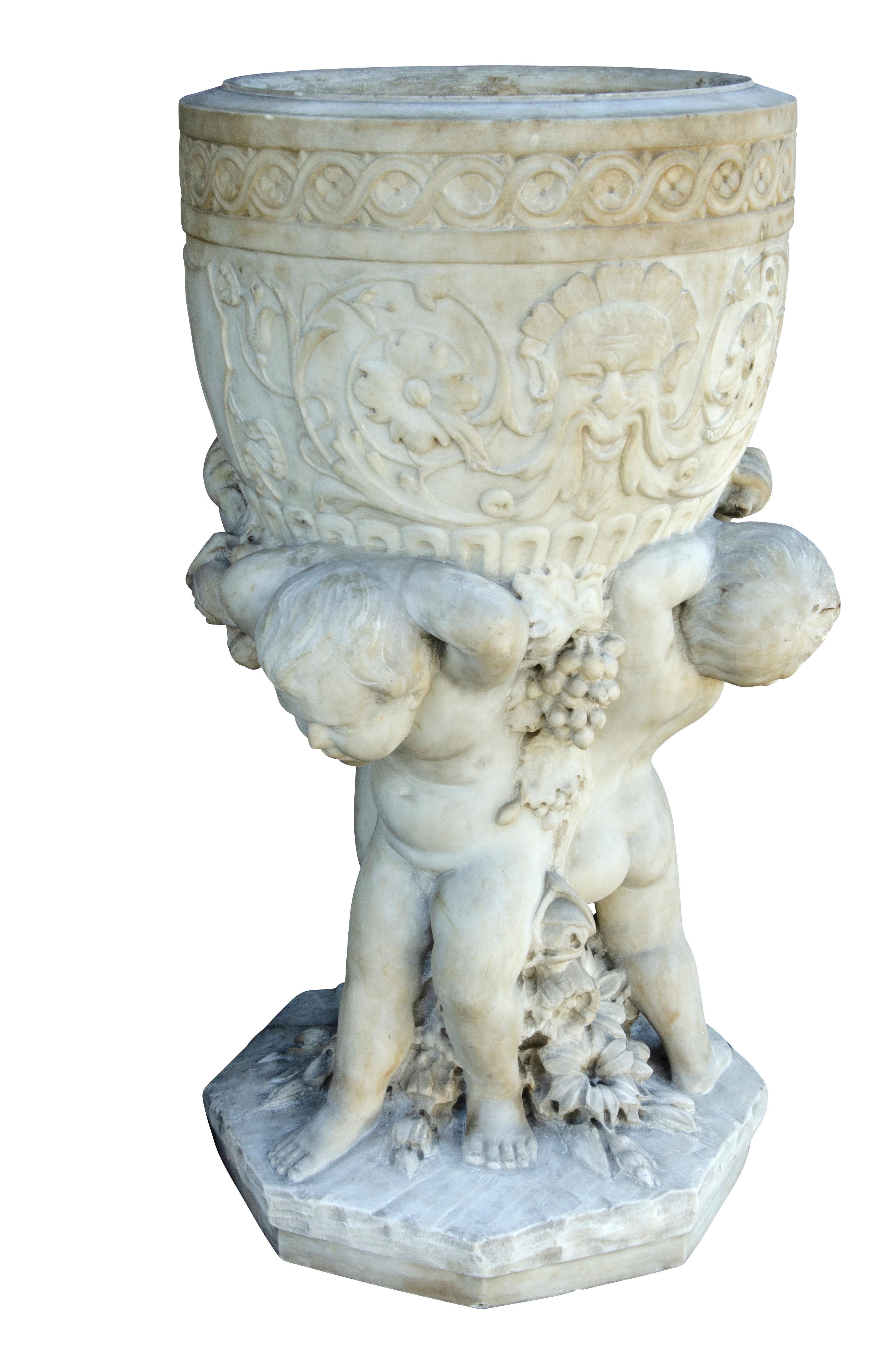With three cherubs on an octagonal base supporting a finely carved urn.