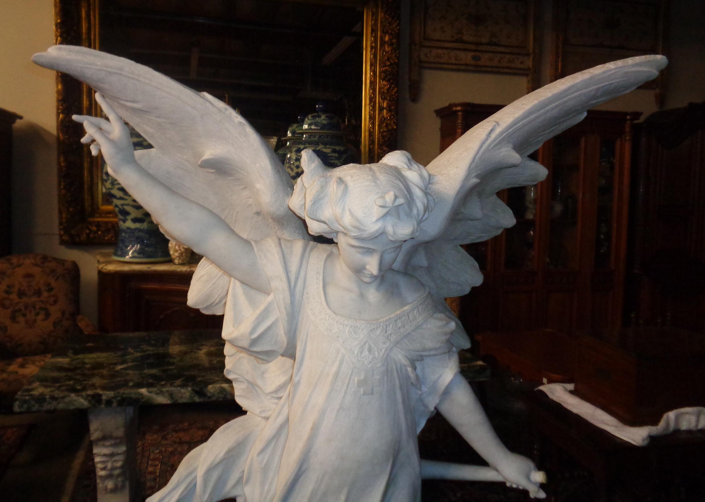 Magnificent life-size Italian Carrara marble sculpture of a winged angel standing on a cloud atop a rectangular base. The right hand is pointing to the heavens and the left hand is holding a trumpet. The angel is carved from a single block of
