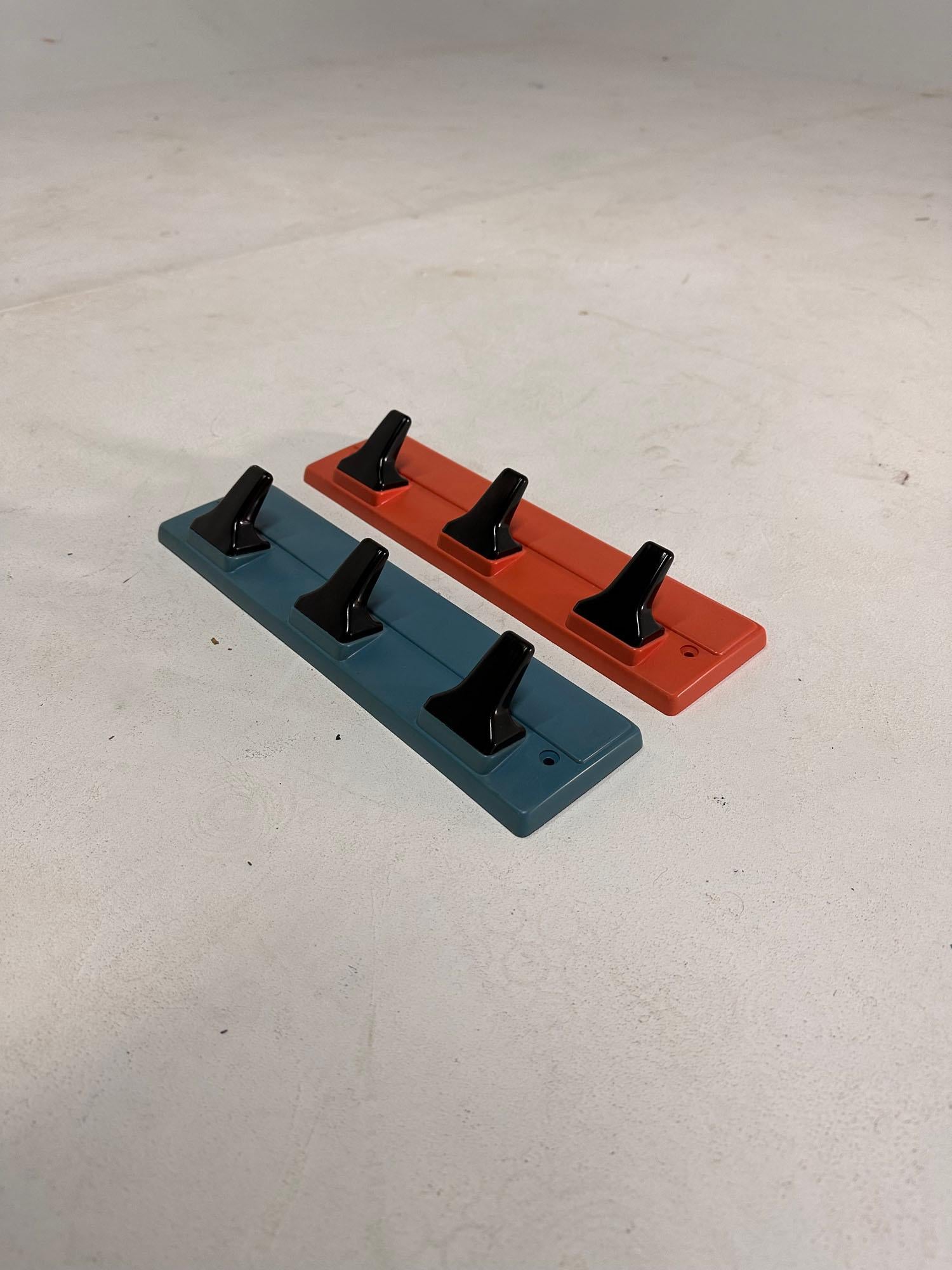 A rare pair of Carrara & Matta coat hooks. Made in Italy in the 1970's. Model DER. Vintage Midcentury Utility Clothes Hooks mounts on Wall with Screws. Made of plastic, bakelite Look. 3 black hooks each on one red and other blue.