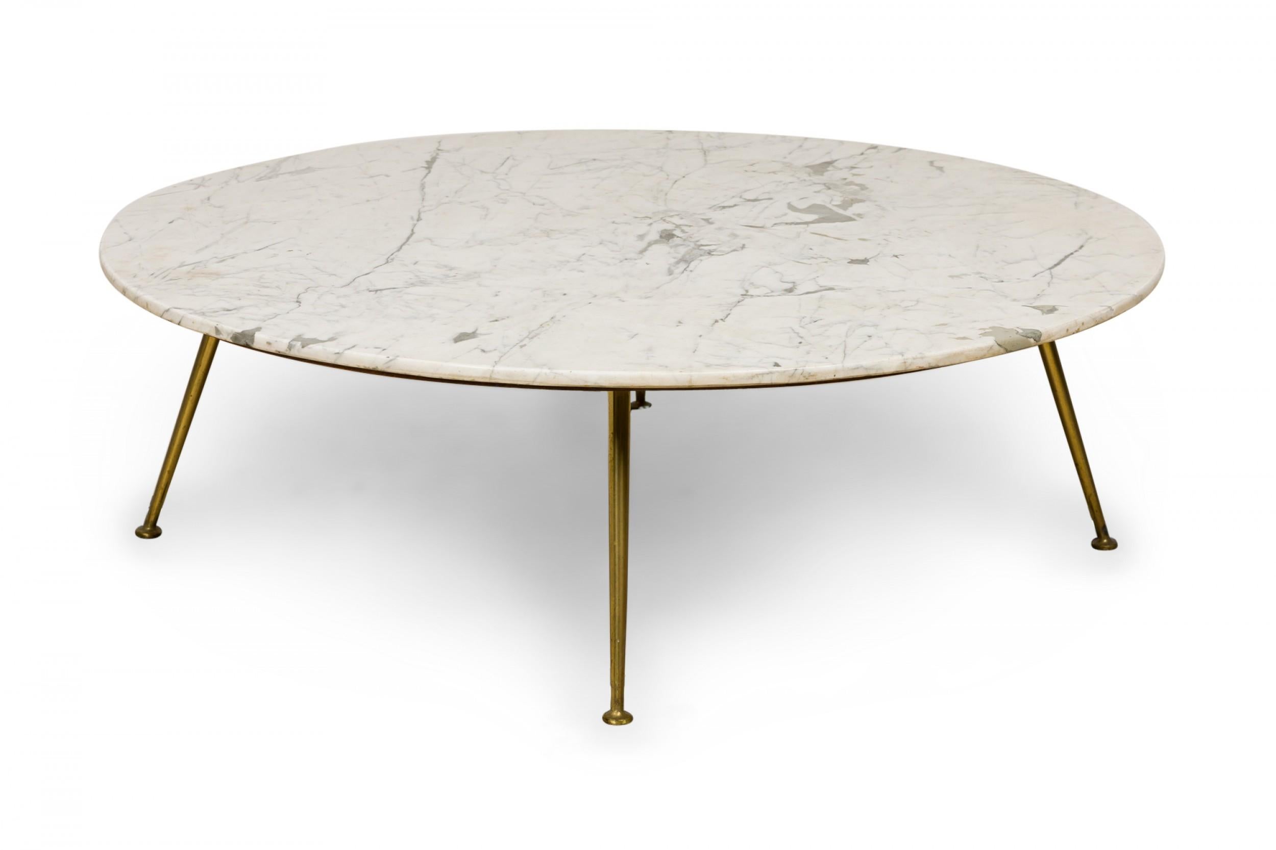 Italian mid-Century circular cocktail / coffee table with a Carrera marble top resting on a wooden platform supported by three tapered brass legs ending in circular feet.