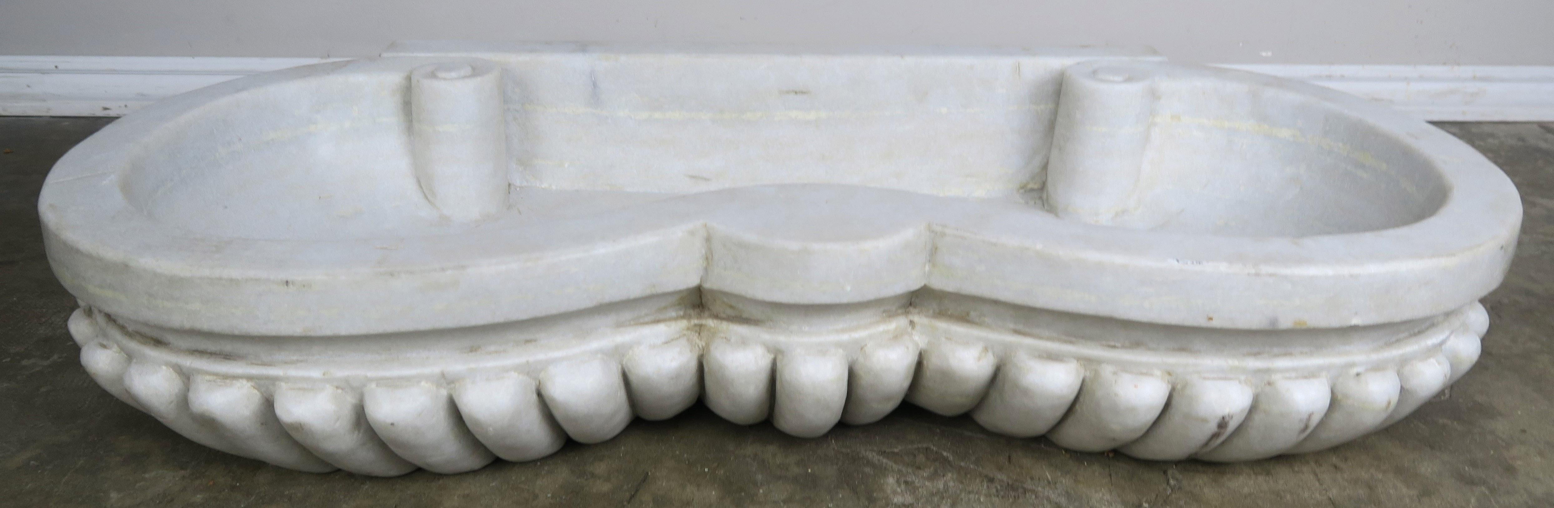 Italian carved Carrara marble sink with a serpentine shaped scalloped body.
 