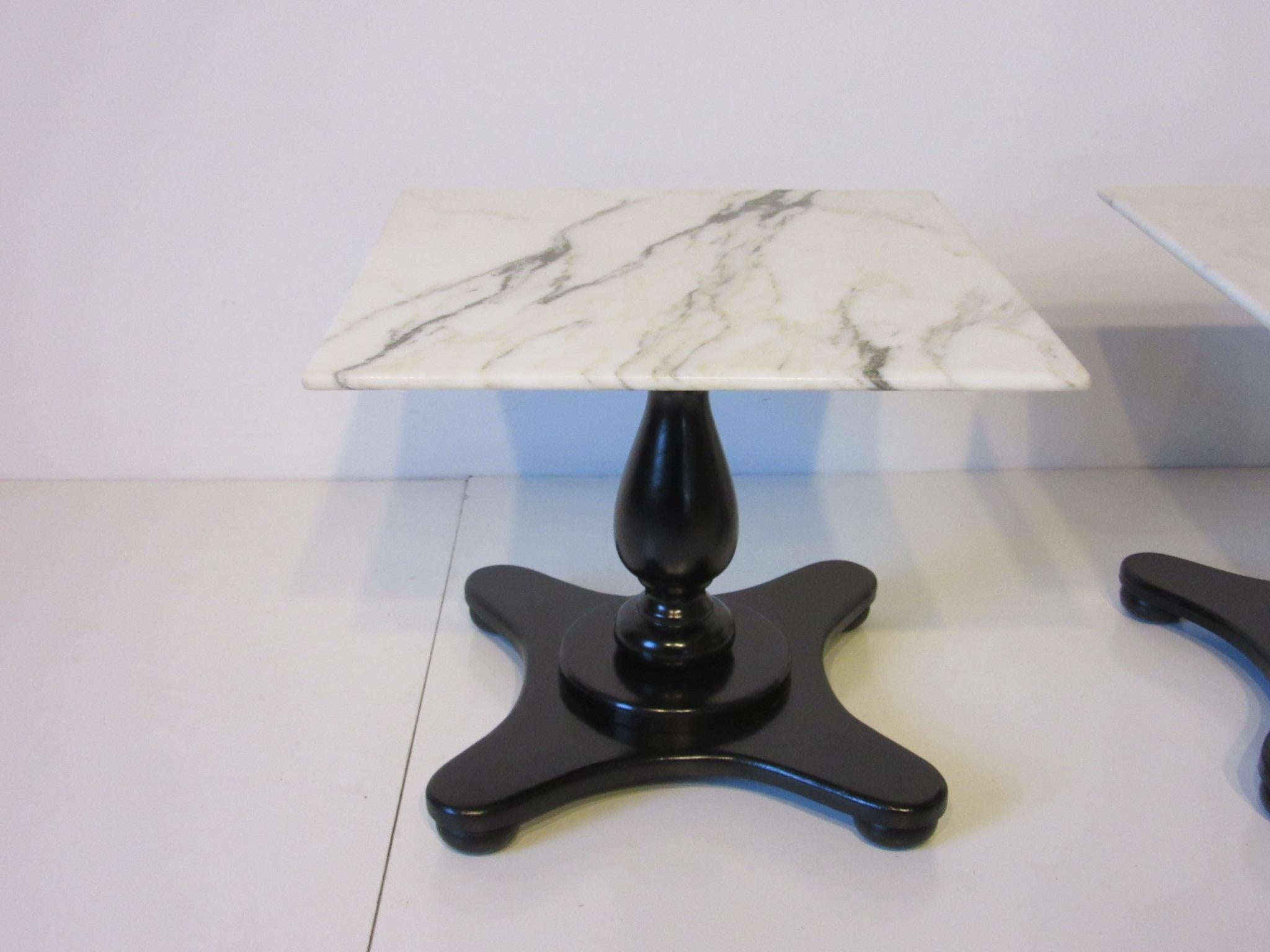 A pair of white Italian Carrera marble topped pedestal end or side tables with lower beveled edges, and satin black wood bases. The perfect mix of traditional Italian and a modern vibe.