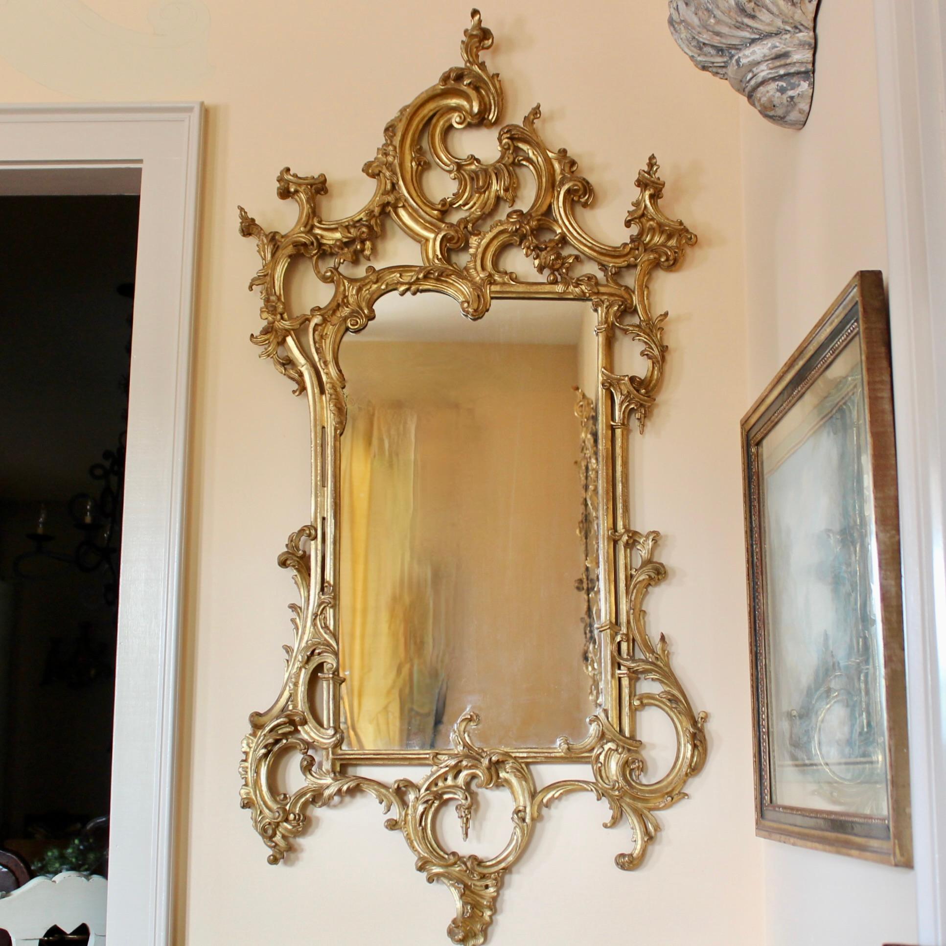 A finely carved Italian giltwood mirror in the George III style with exuberant asymmetrical Rococo motifs well executed and well balanced. Good condition. The gilding is bright with light wear and small losses and minor distress. Mirror plate with