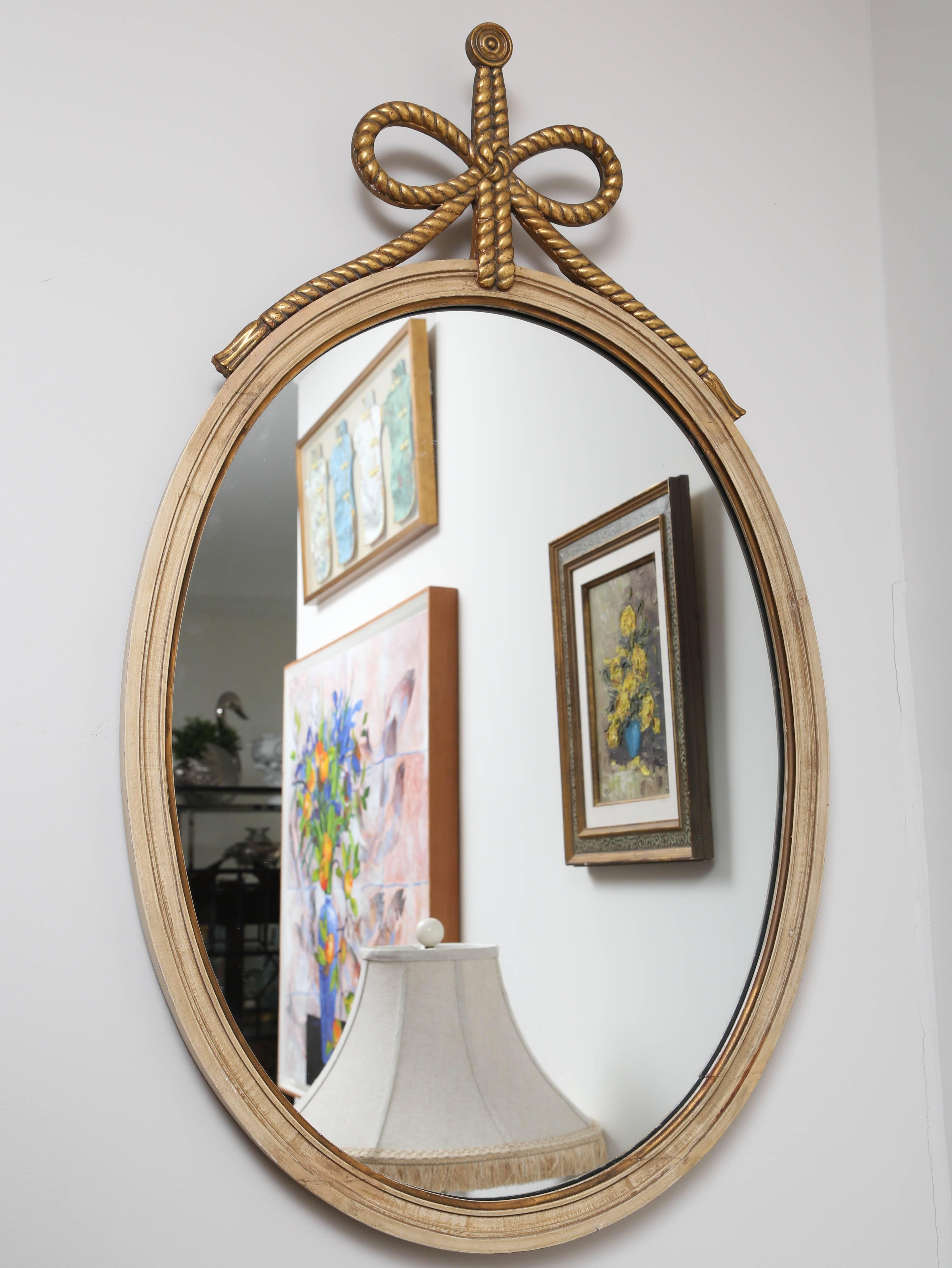 Italian cream and gold gilt oval mirror topped with a rope bow detail.