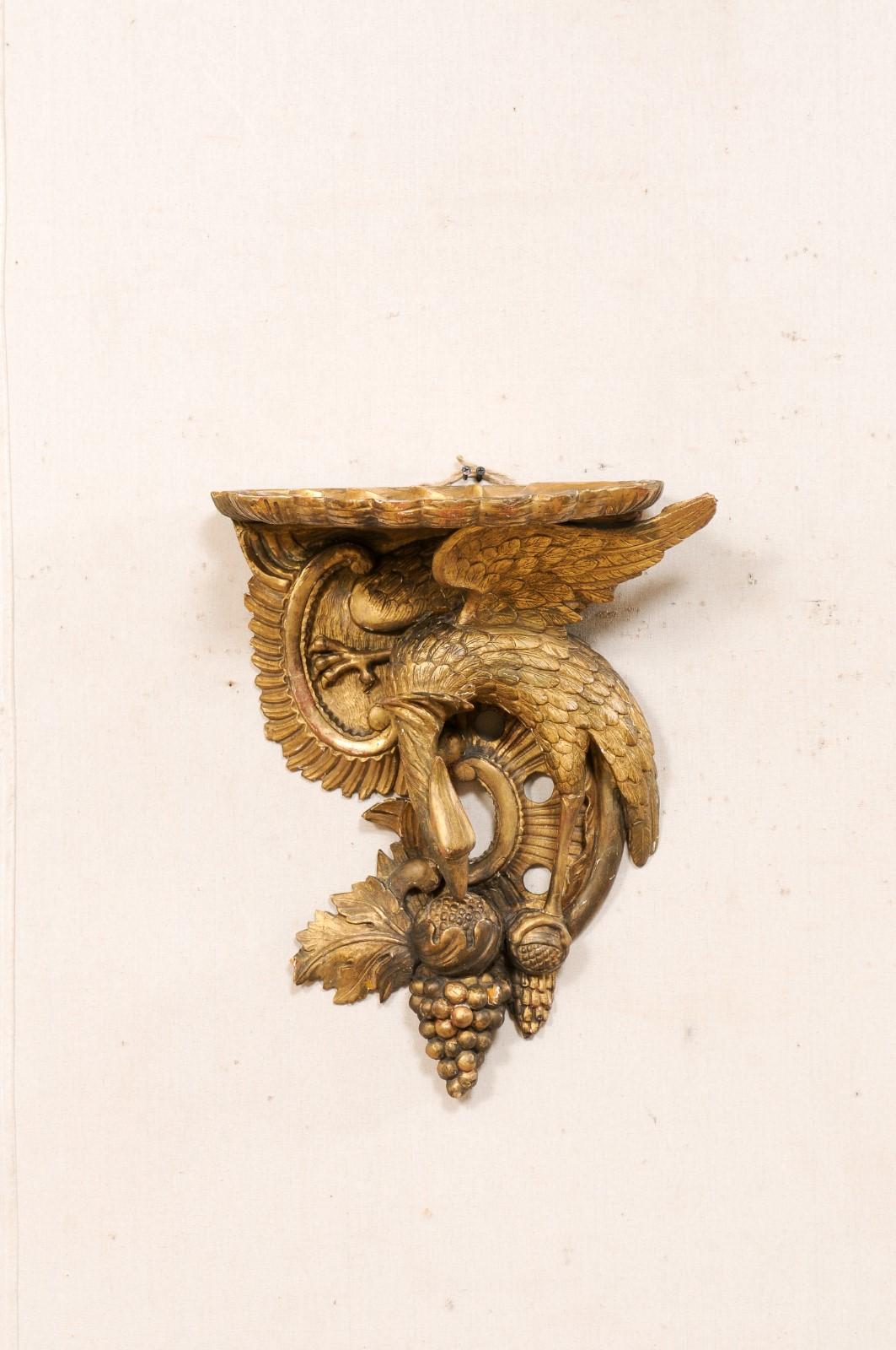 An Italian carved and gilt wood wall-hanging bracket in eagle, grape, and shell motif, 19th century. This antique architectural wall decorations from Italy features a three-dimensionally carved bird (eagle), grapes, and scrolling-foliate accents,
