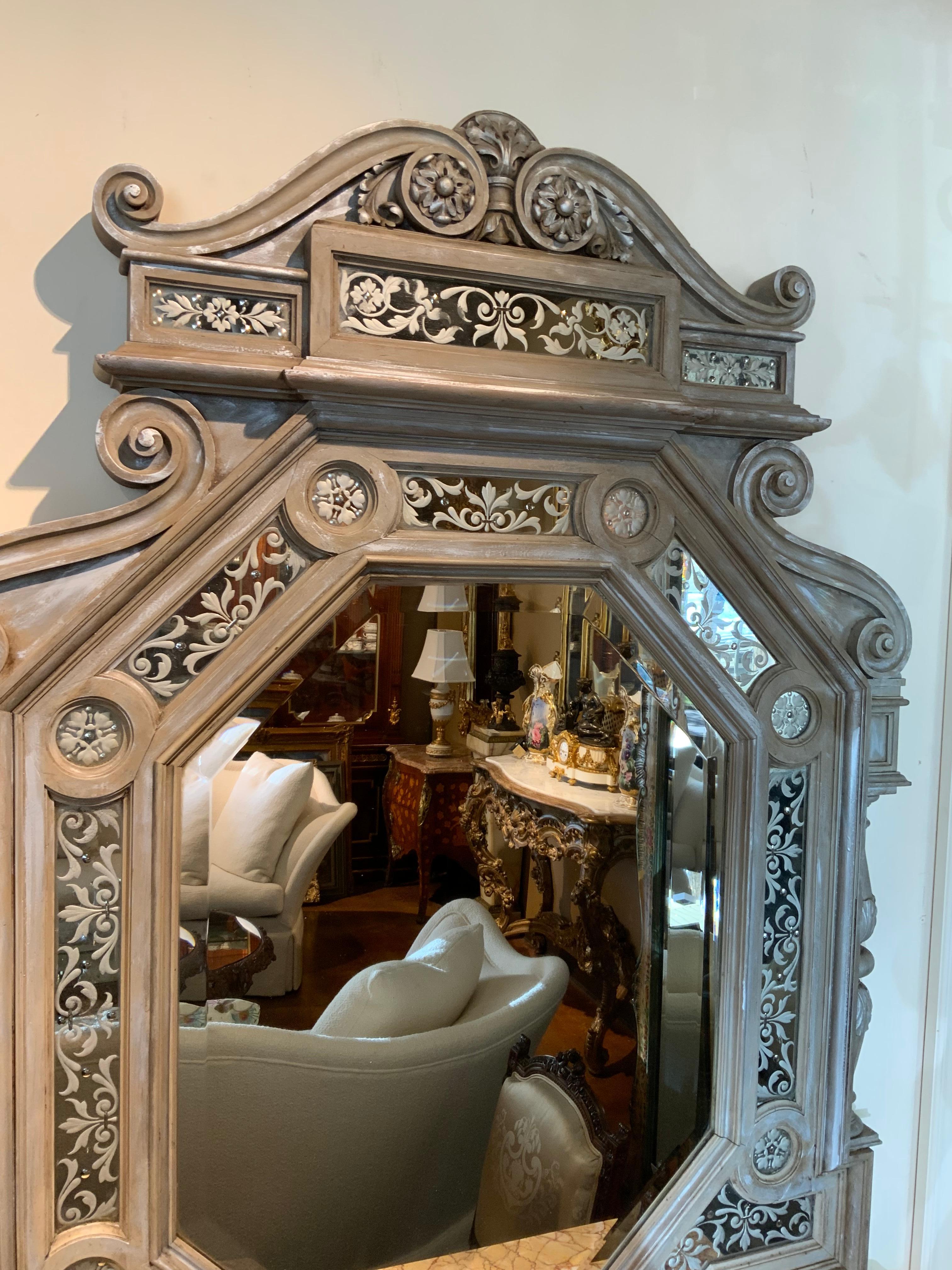 A very special look in a grisalle hue with silver highlights 
Make this piece appealing. It is deeply paneled to give it
Depth and inlaid mirrors are etched in a beautiful swirl design. 
Carved posts on each side have detail carving. A cartouche