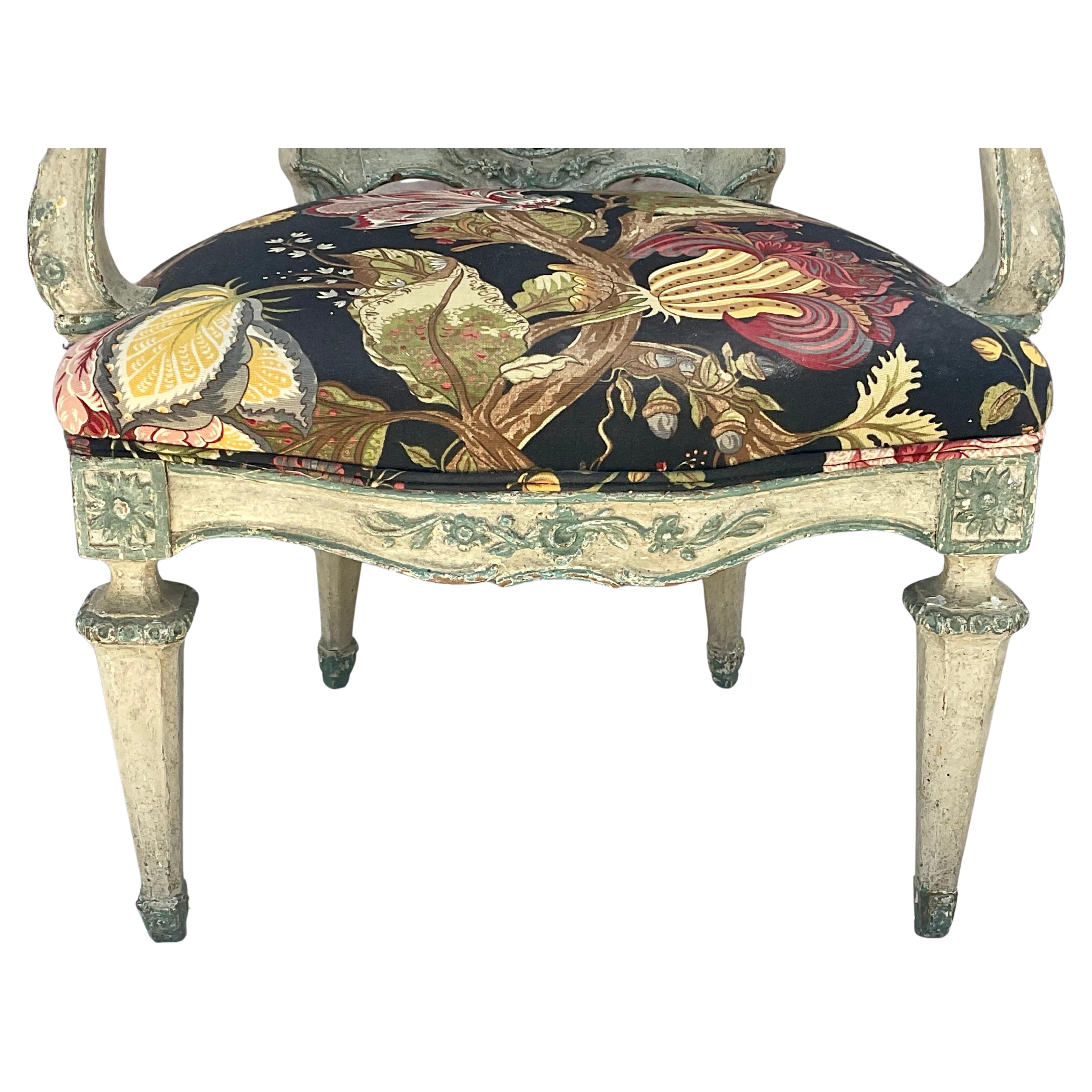 Fauteuil néoclassique italien du XVIIIe siècle, sculpté et peint. Le cadre du Fauteuil est en bois finement sculpté. Le dossier est orné d'un cimier sculpté représentant une tête masculine de profil dans un médaillon arrondi, encadré de rinceaux. Le
