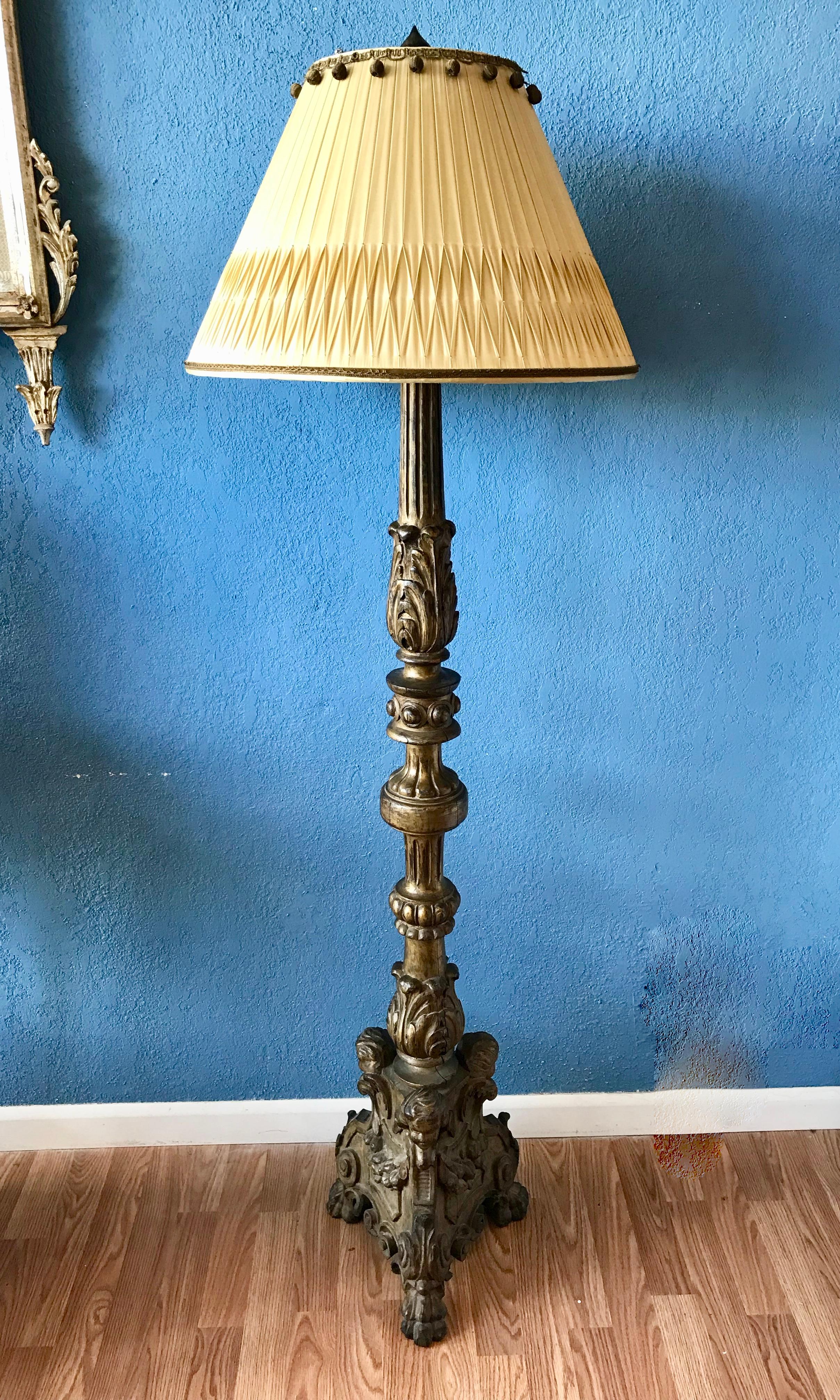 Die aufwändig und eindrucksvoll geschnitzte Lampe aus vergoldetem Holz ist mit 
und Puttengesichtern am Sockel ausgestattet. (Der Schirm ist nicht enthalten).