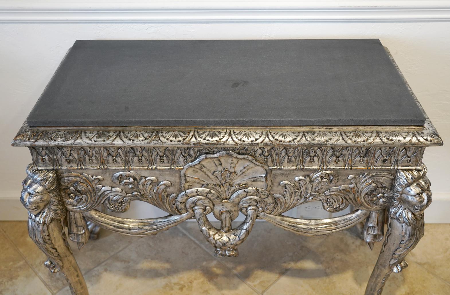 This ornately carved Italian Baroque style console table dating to the 'Belle Époque Period' in the late 1800s features four lion head carved cabriole legs with claw and ball feet centering carved laurel swags, foliate scrolls and a central shell