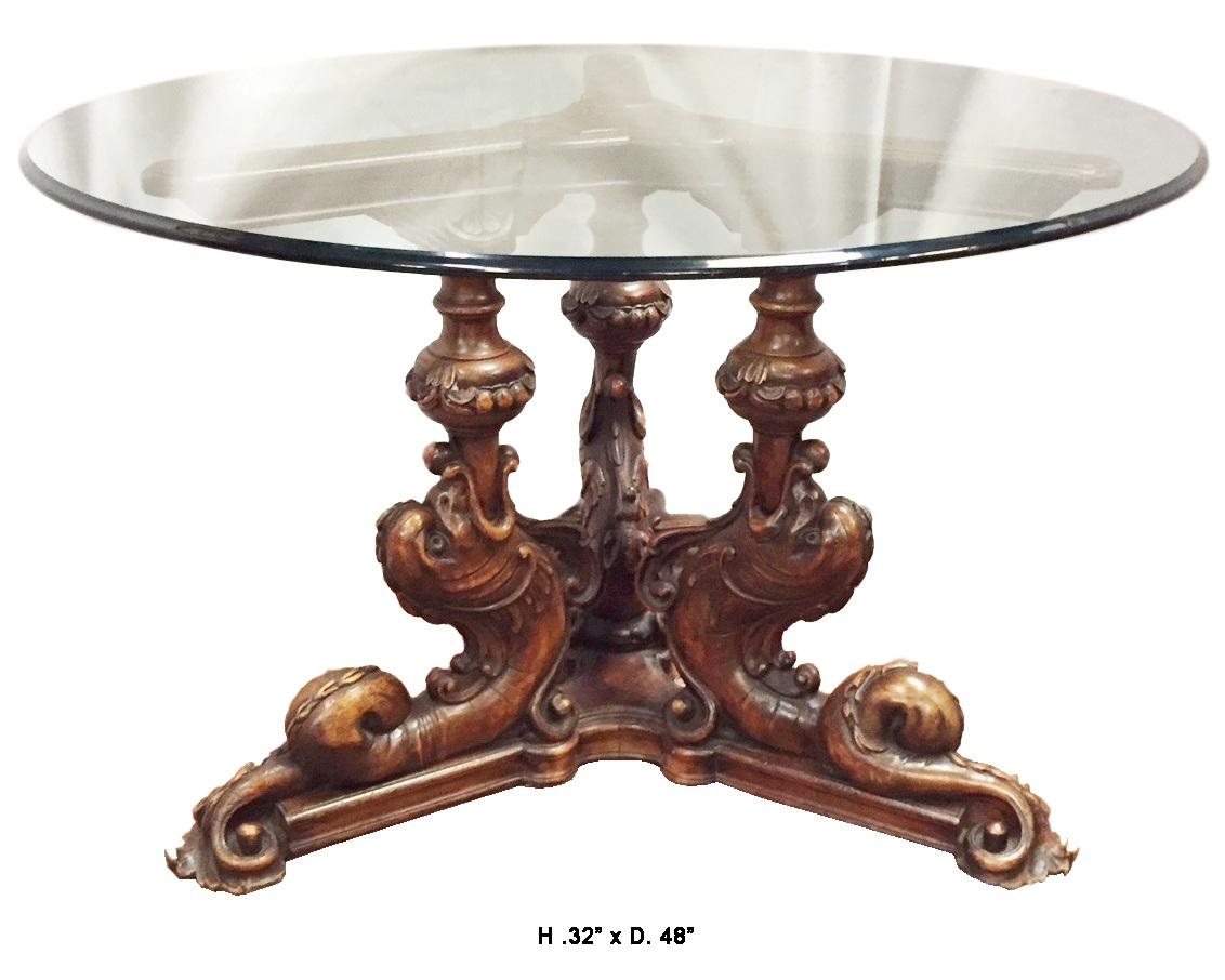 Outstanding 19th century Baroque style Italian carved walnut round table. 
The round half inch thick glass table with curved edge over beautifully carved walnut tripod pedestal table with dolphin motif. 
Beautiful patina. 
Measures: H. 32