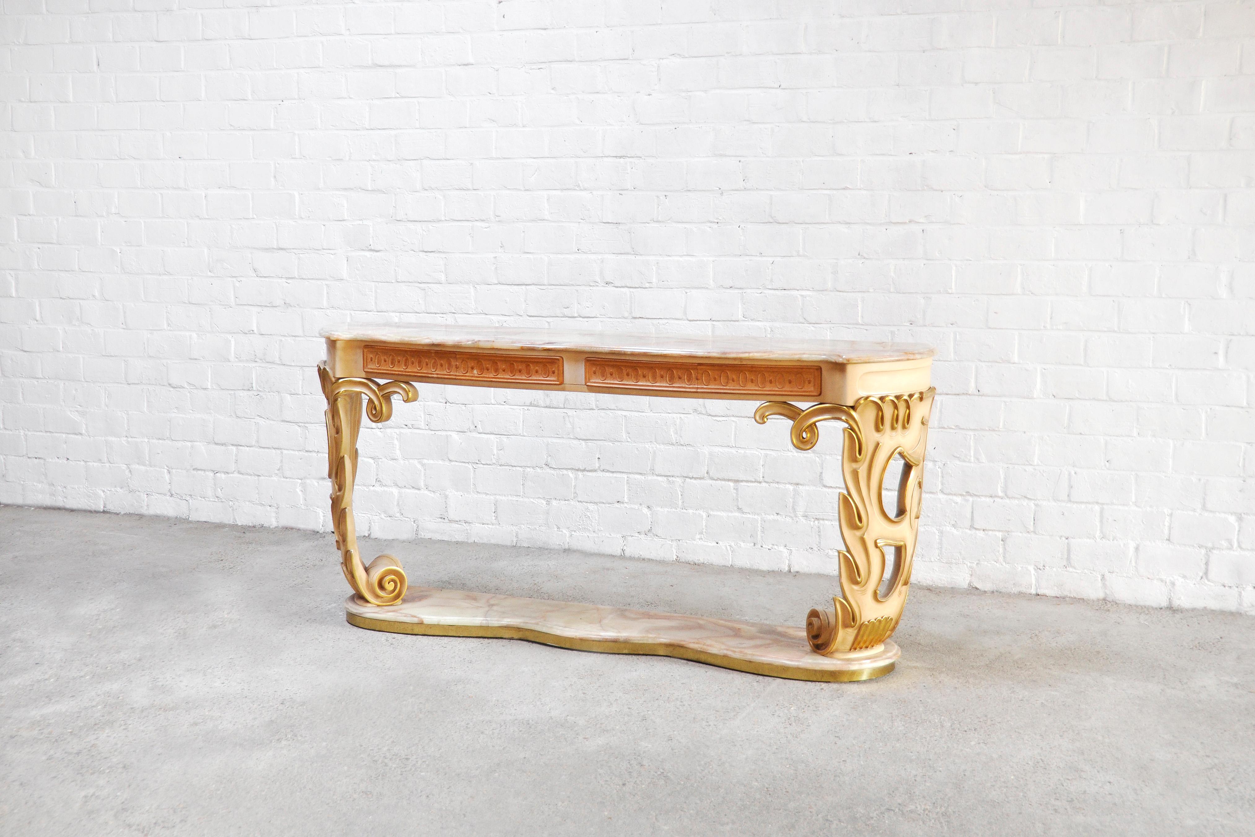 An impressive and large Italian console in lacquered and gilded carved wood. Finished with a large top and base in onyx. Under the onyx top are four drawers for storage. This unique console presents very fine details and a high production quality.